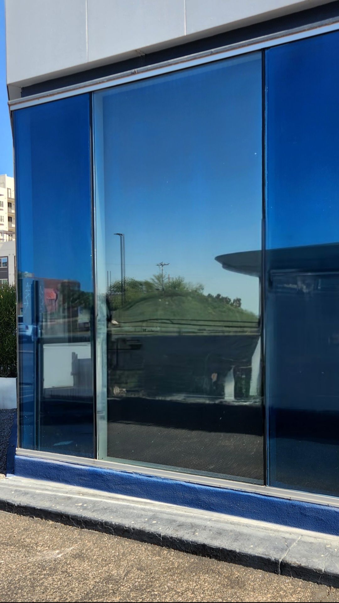 Blue-tinted glass storefront reflecting the sky and buildings.