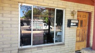 Modern office building with blue-tinted windows against a blue sky with white clouds.