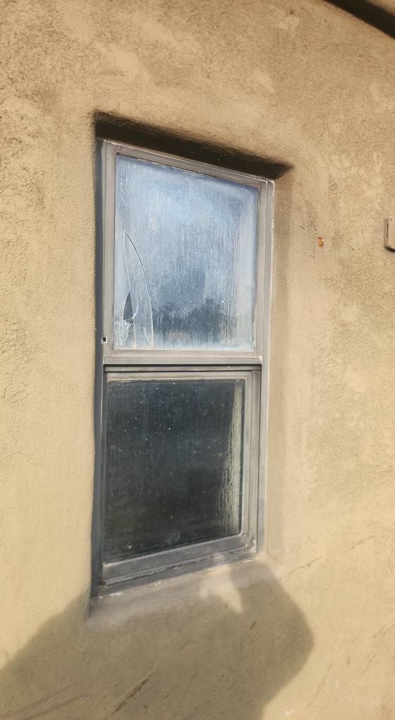 A rectangular window on a tan stucco wall. The glass is cloudy.