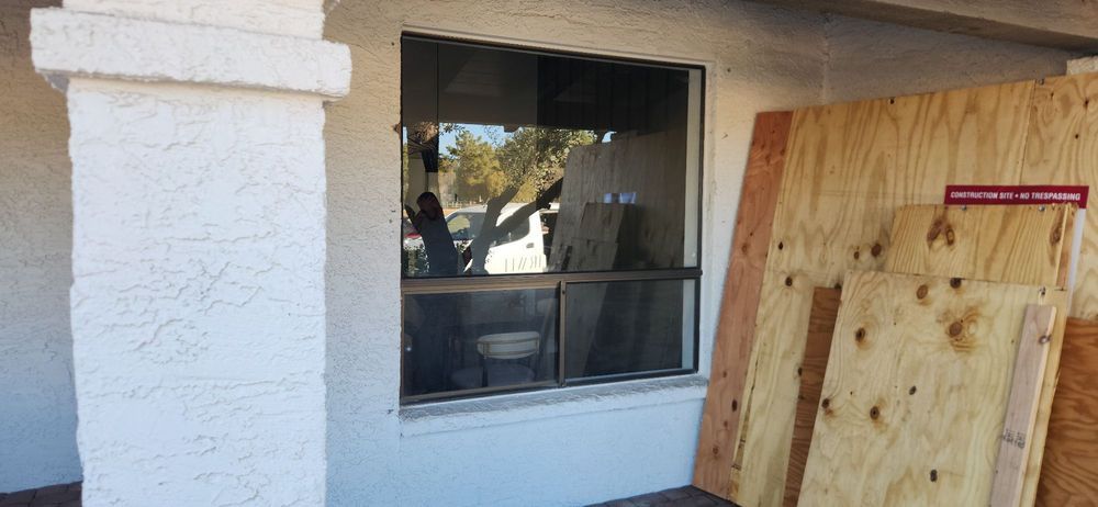 Exterior of a building with a window and plywood boards stacked next to it, possibly for protection.