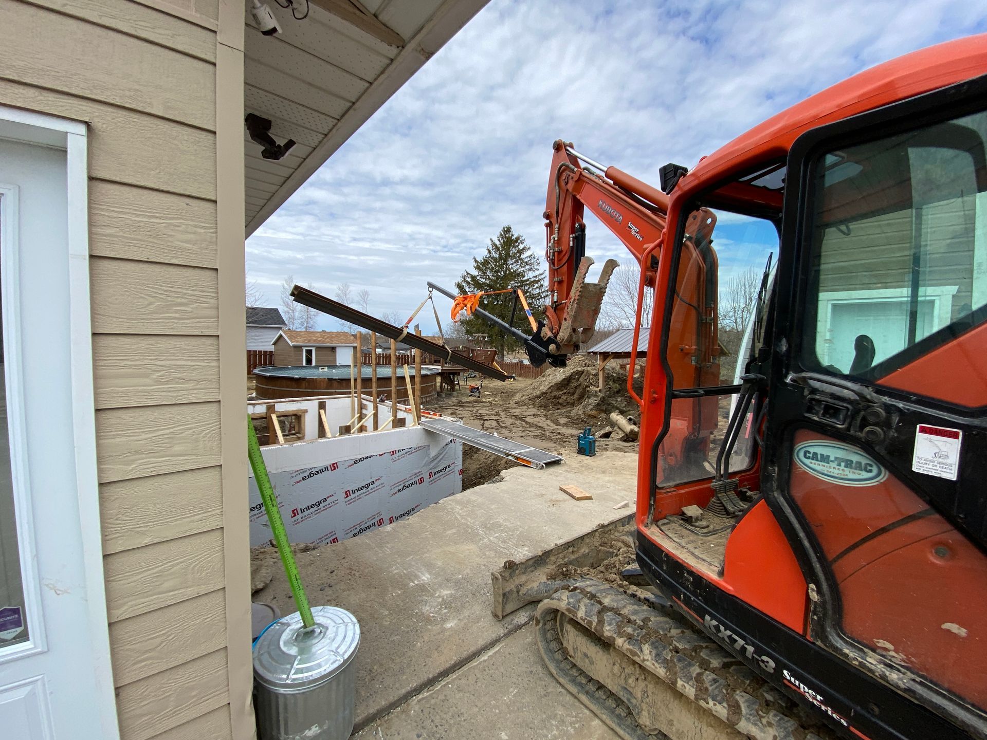 Une grande excavatrice orange est assise devant une maison.