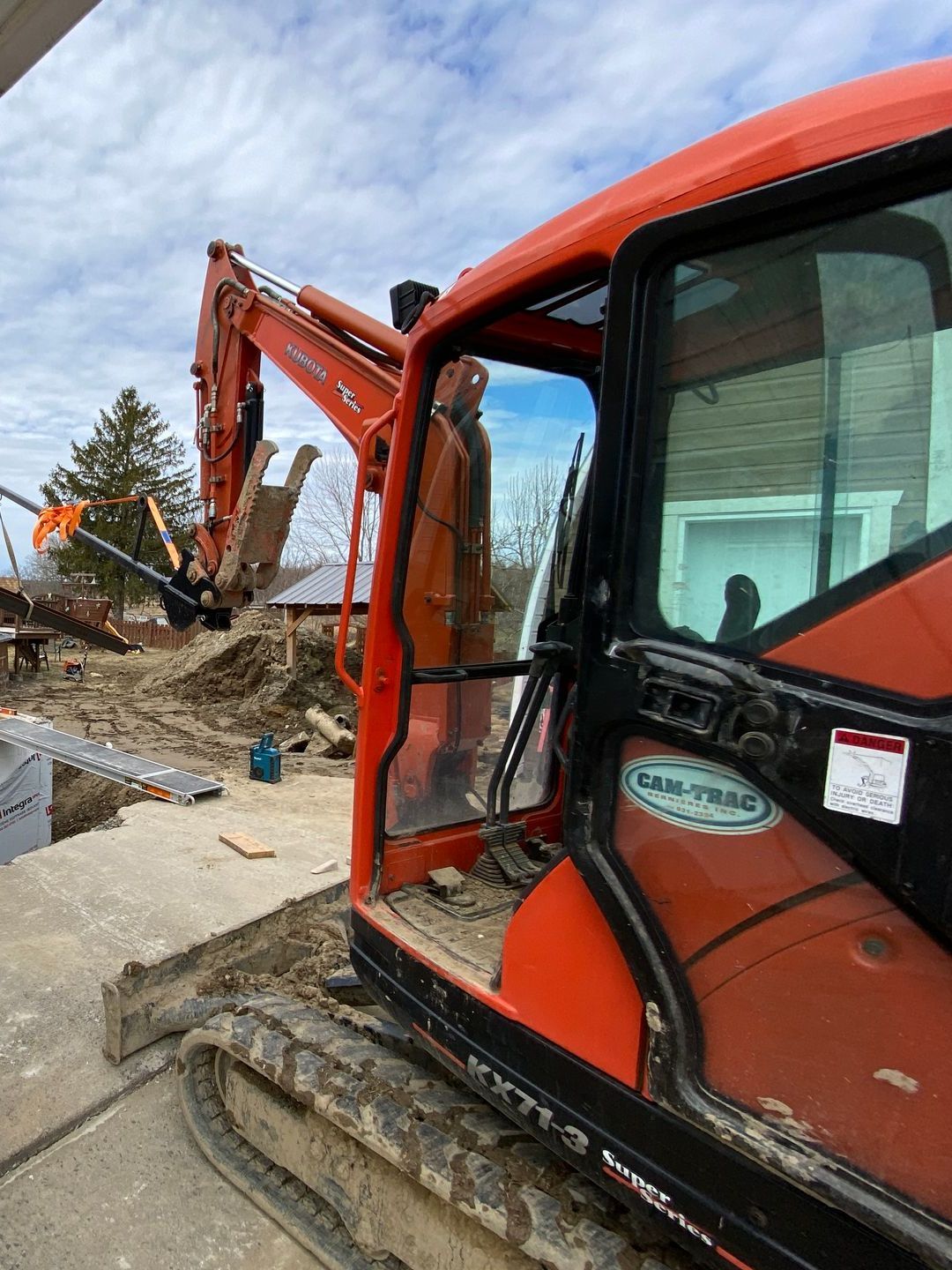 Une grande excavatrice orange est posée sur un champ de terre.