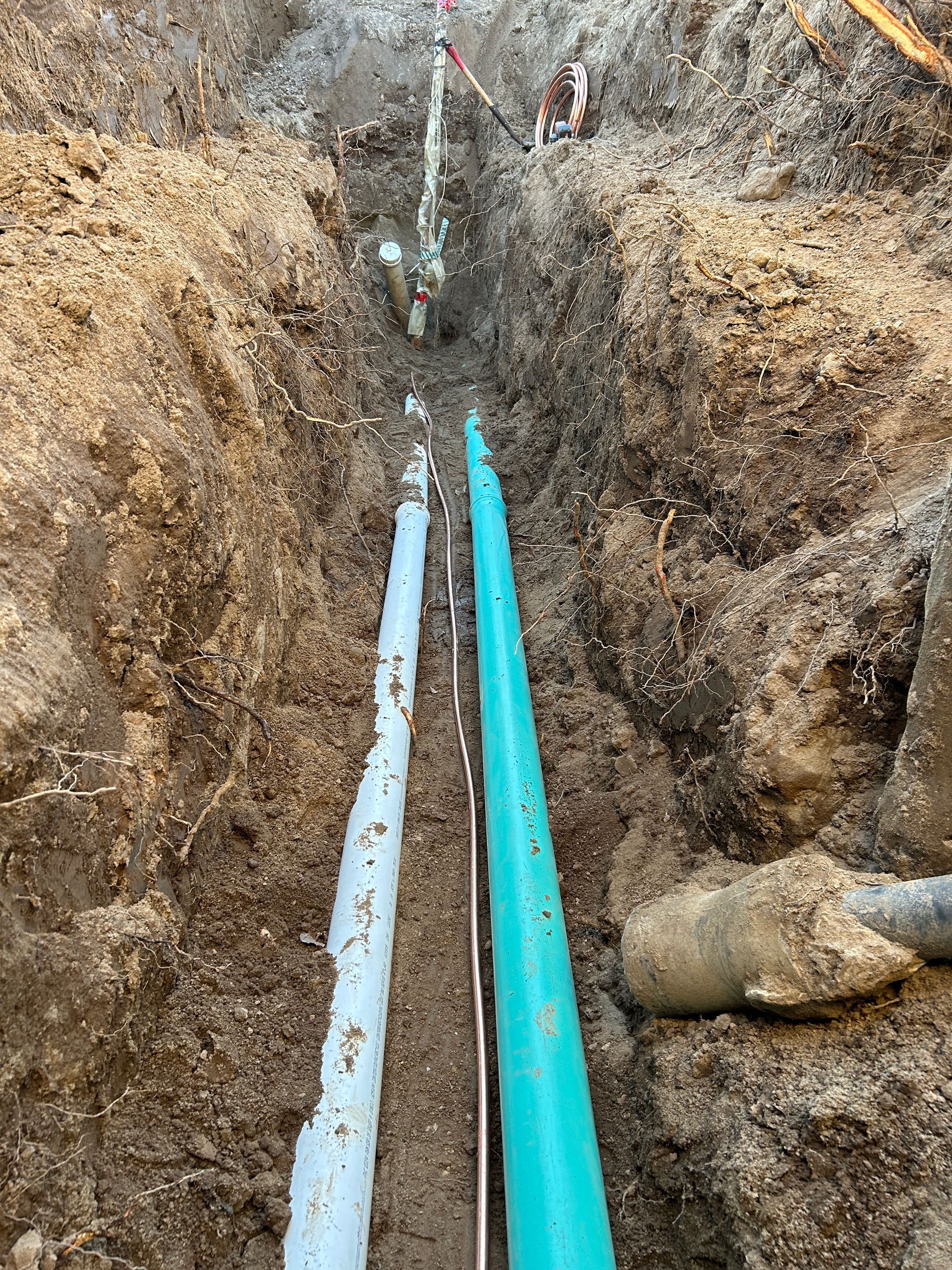 Deux tuyaux sont en train d'être installés dans une tranchée dans la terre.
