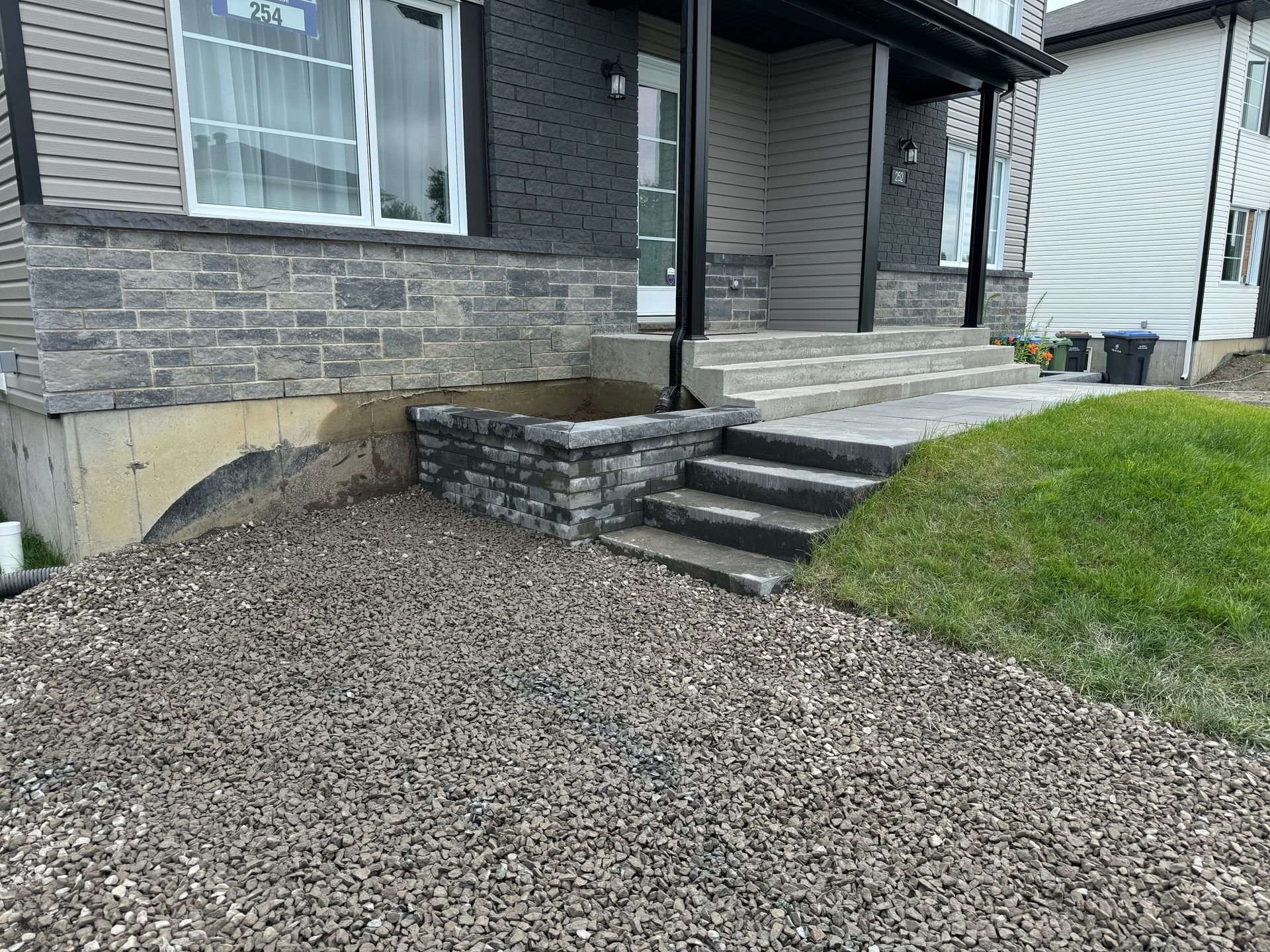 Une maison avec des escaliers et une allée de gravier devant elle.