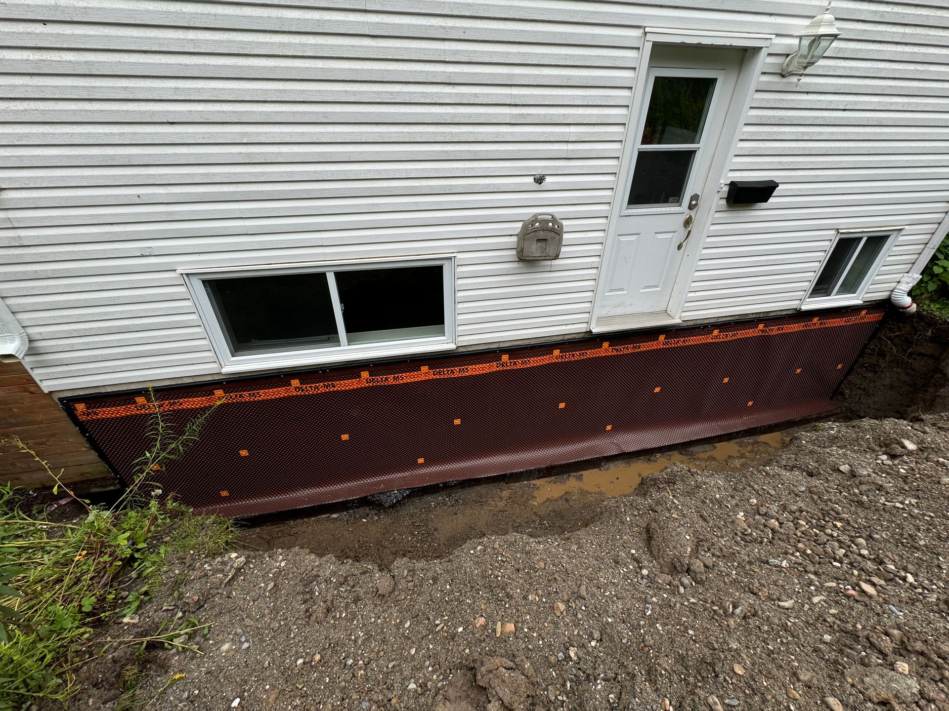 Une maison blanche avec un trou dans le sol devant elle.