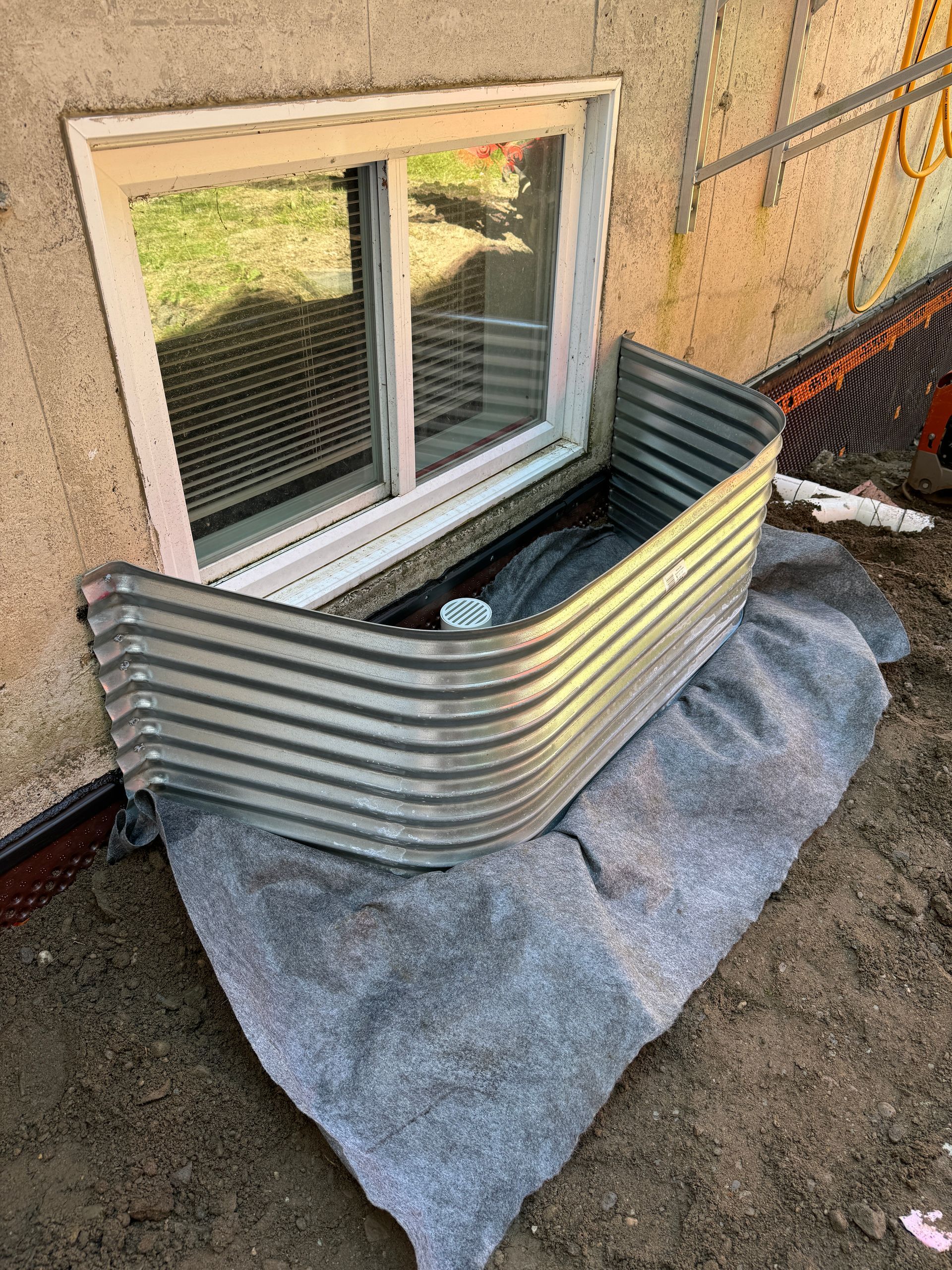 Une fenêtre dans un sous-sol avec une barrière métallique autour.