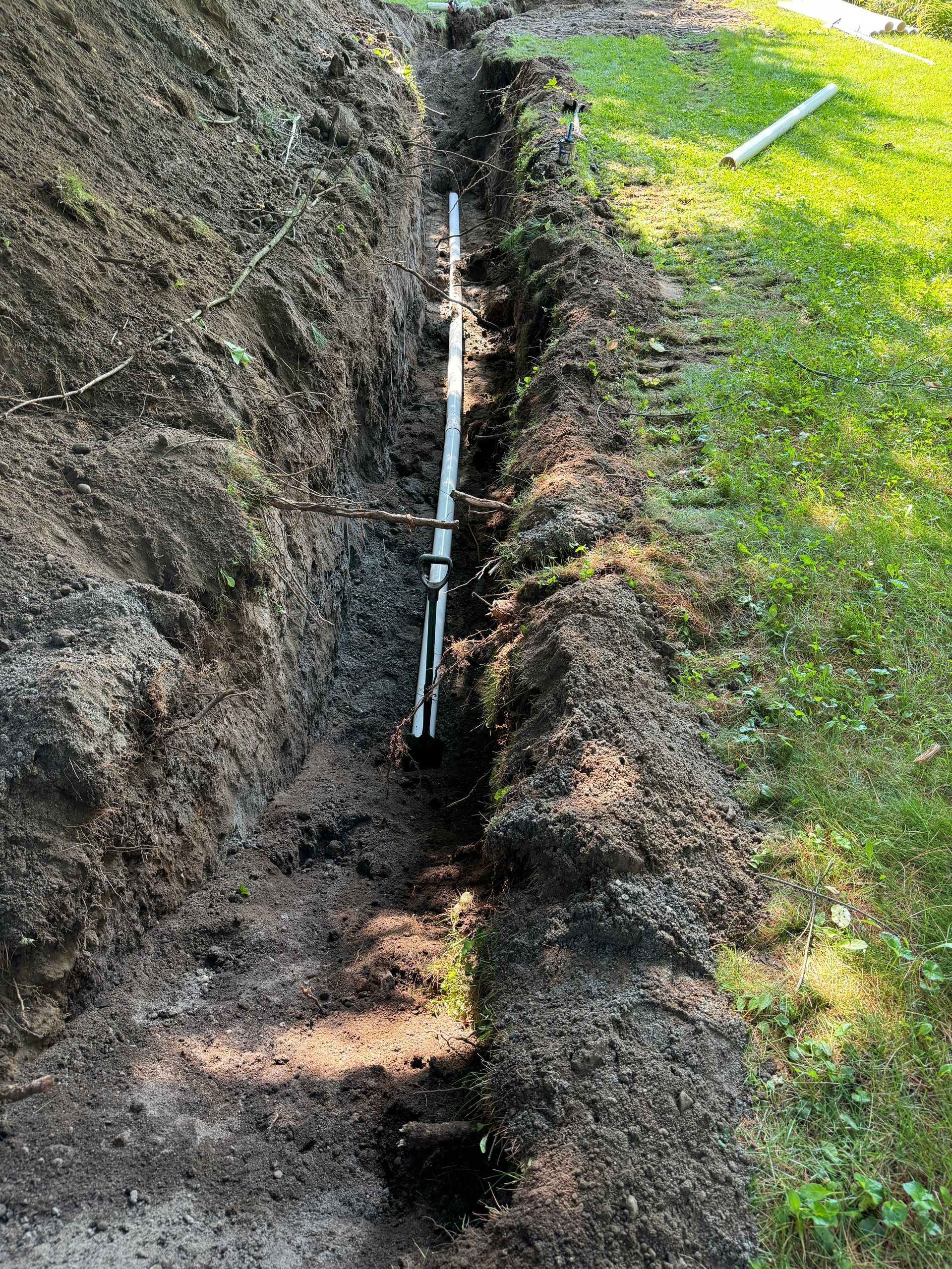 Un tuyau est en train d'être installé dans une tranchée dans le sol.