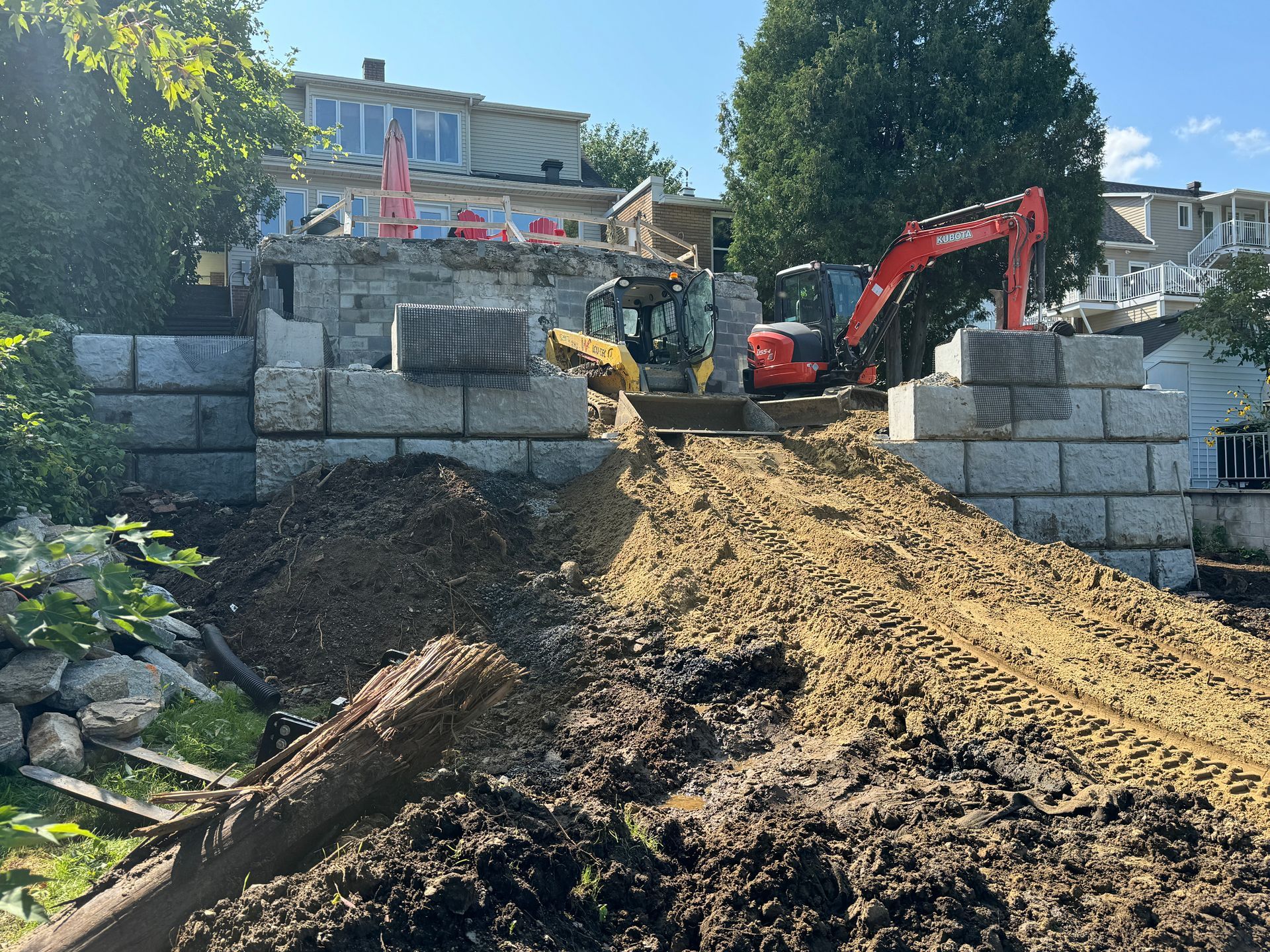 Un chantier avec un gros tas de terre et un bulldozer.