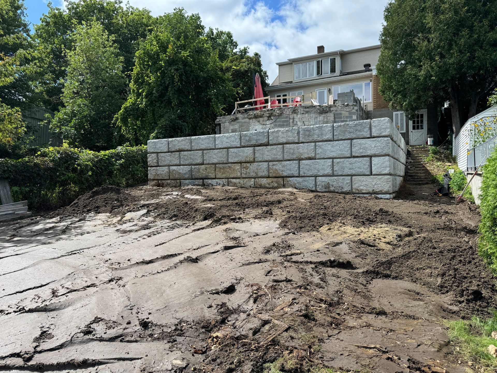 Un grand mur de briques est en cours de construction dans l'arrière-cour d'une maison.