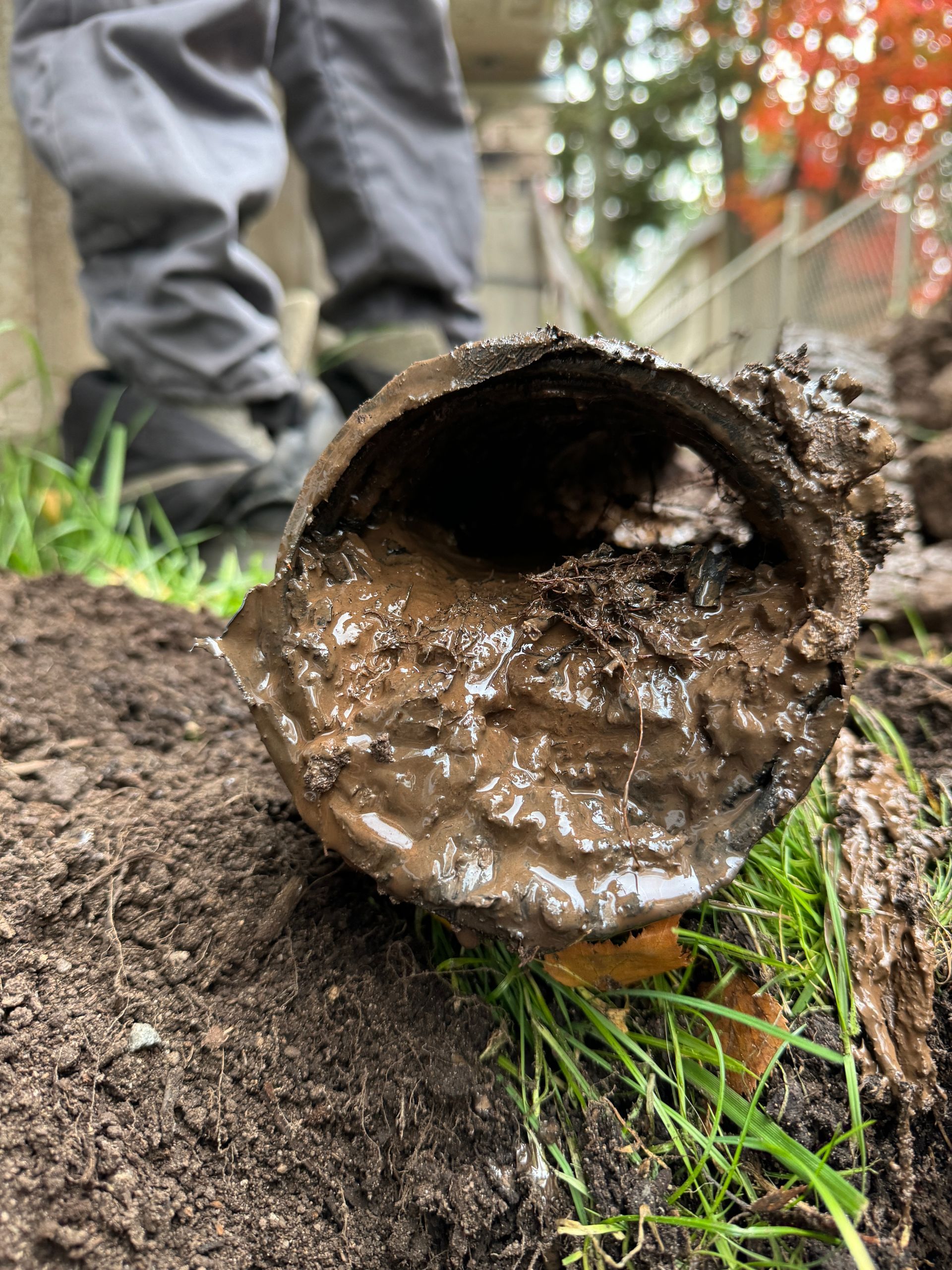 Un gros plan d'un tuyau boueux posé sur un tas de terre.
