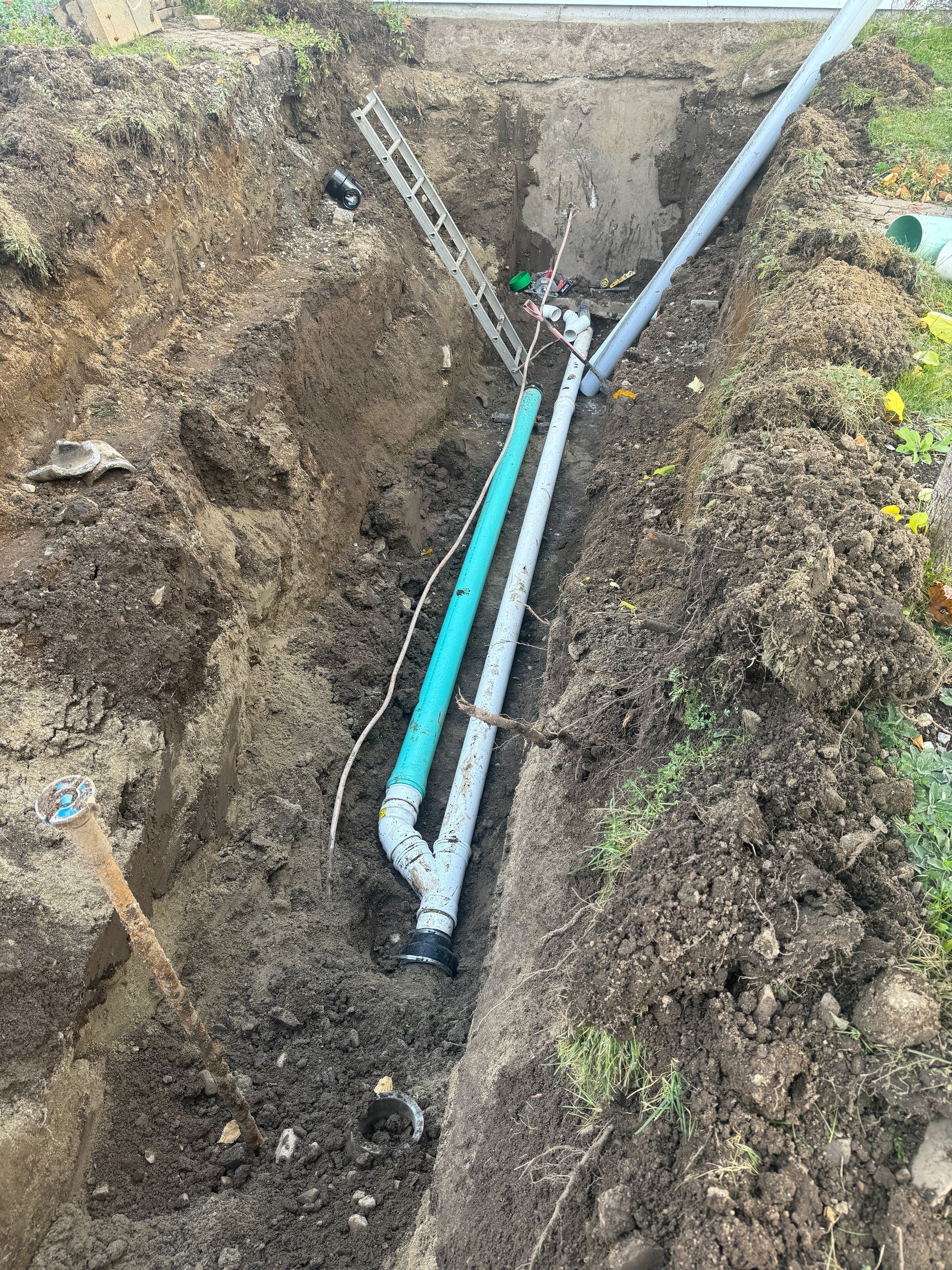 Un tuyau de drainage est en train d'être installé dans un trou dans le sol.