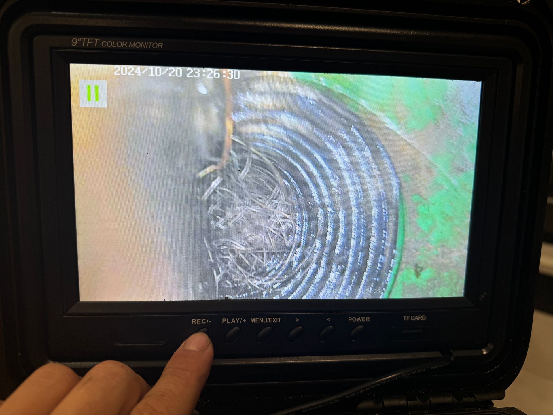 Une personne pointe du doigt un écran qui montre un trou dans un tuyau.