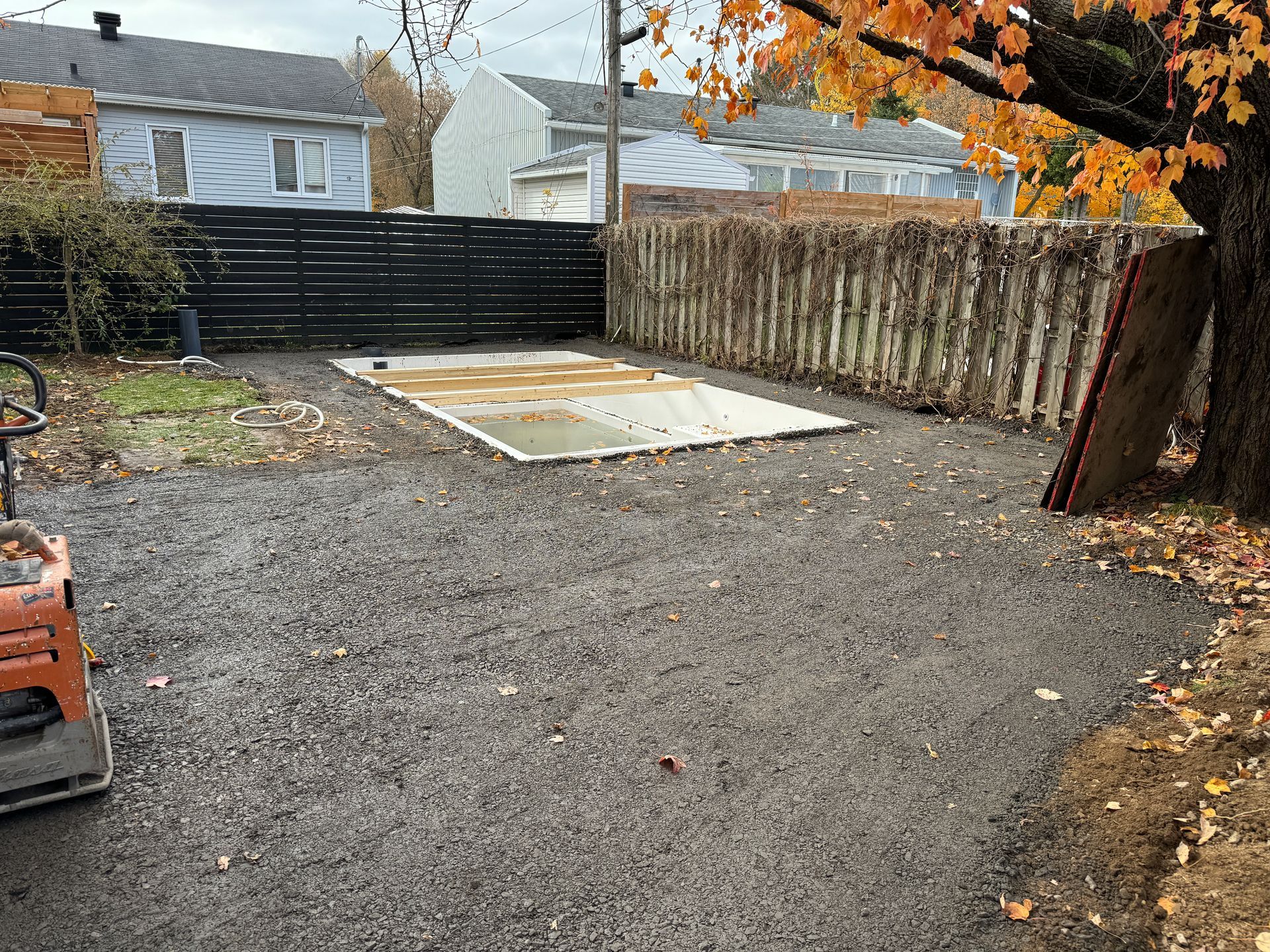 Une cour arrière avec une clôture et une dalle de béton au milieu.