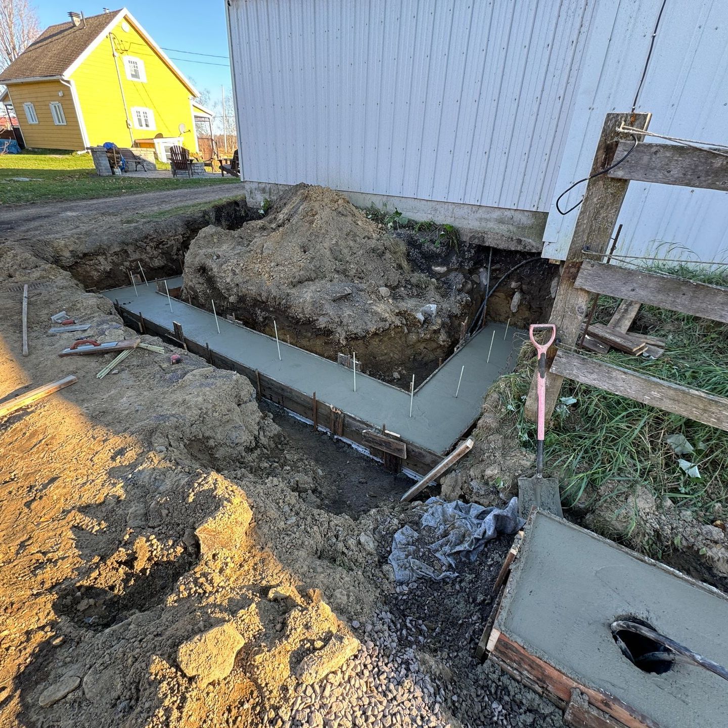 Une fondation en béton est en train d'être construite devant une maison.