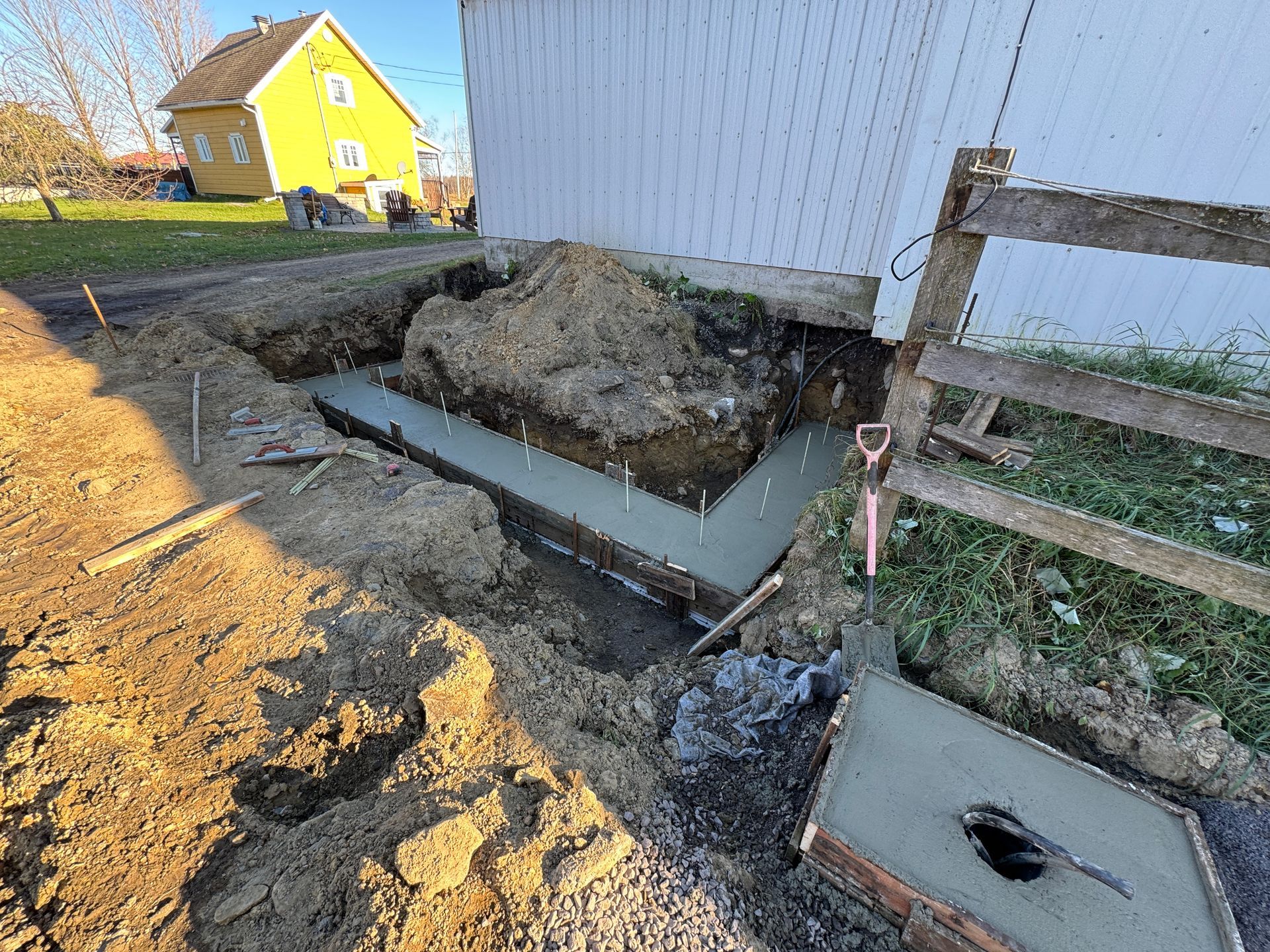 Une fondation en béton est en train d'être construite devant une maison.