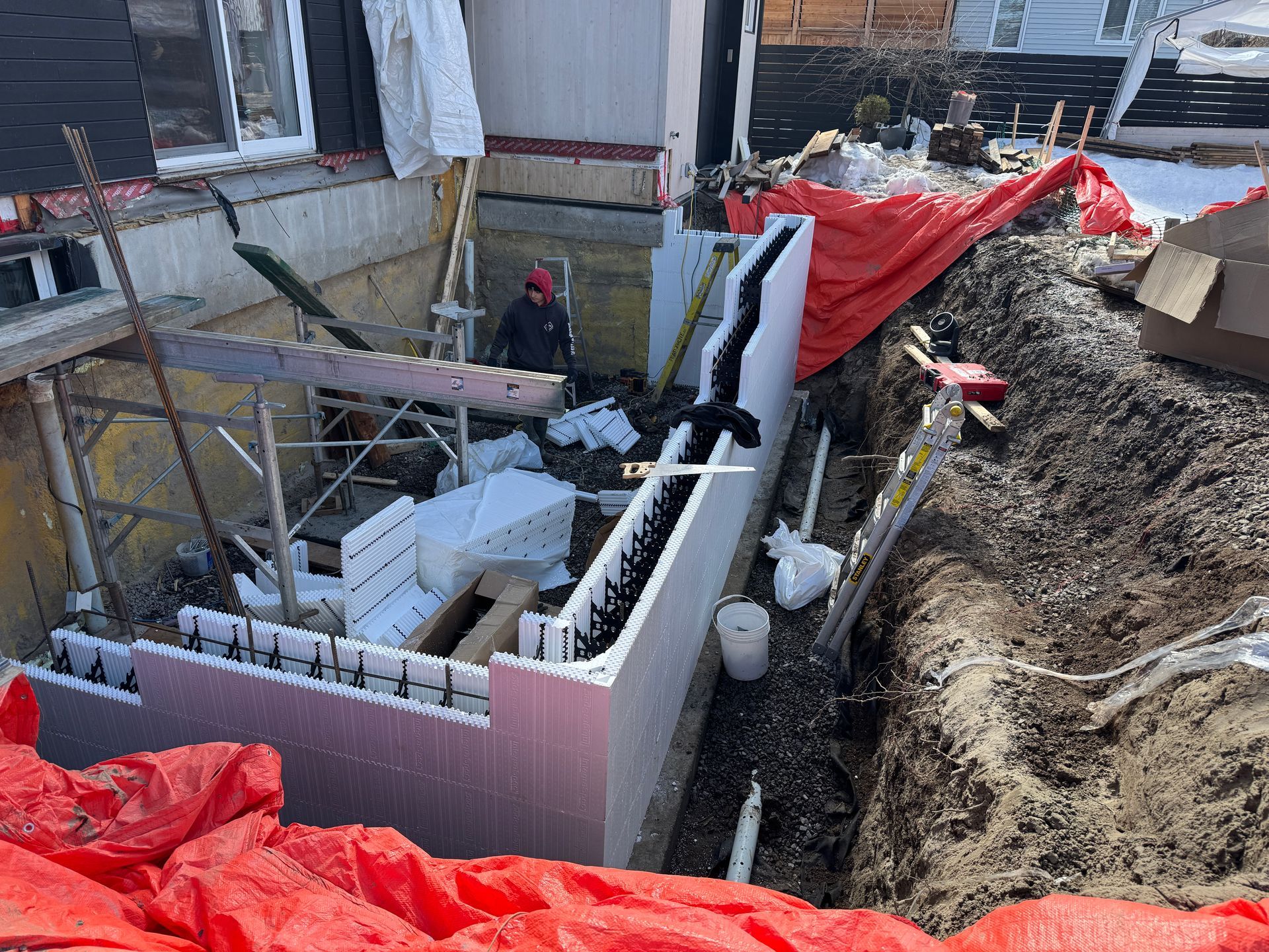 Un homme se tient debout dans un trou dans le sol à côté d'un bâtiment en construction.