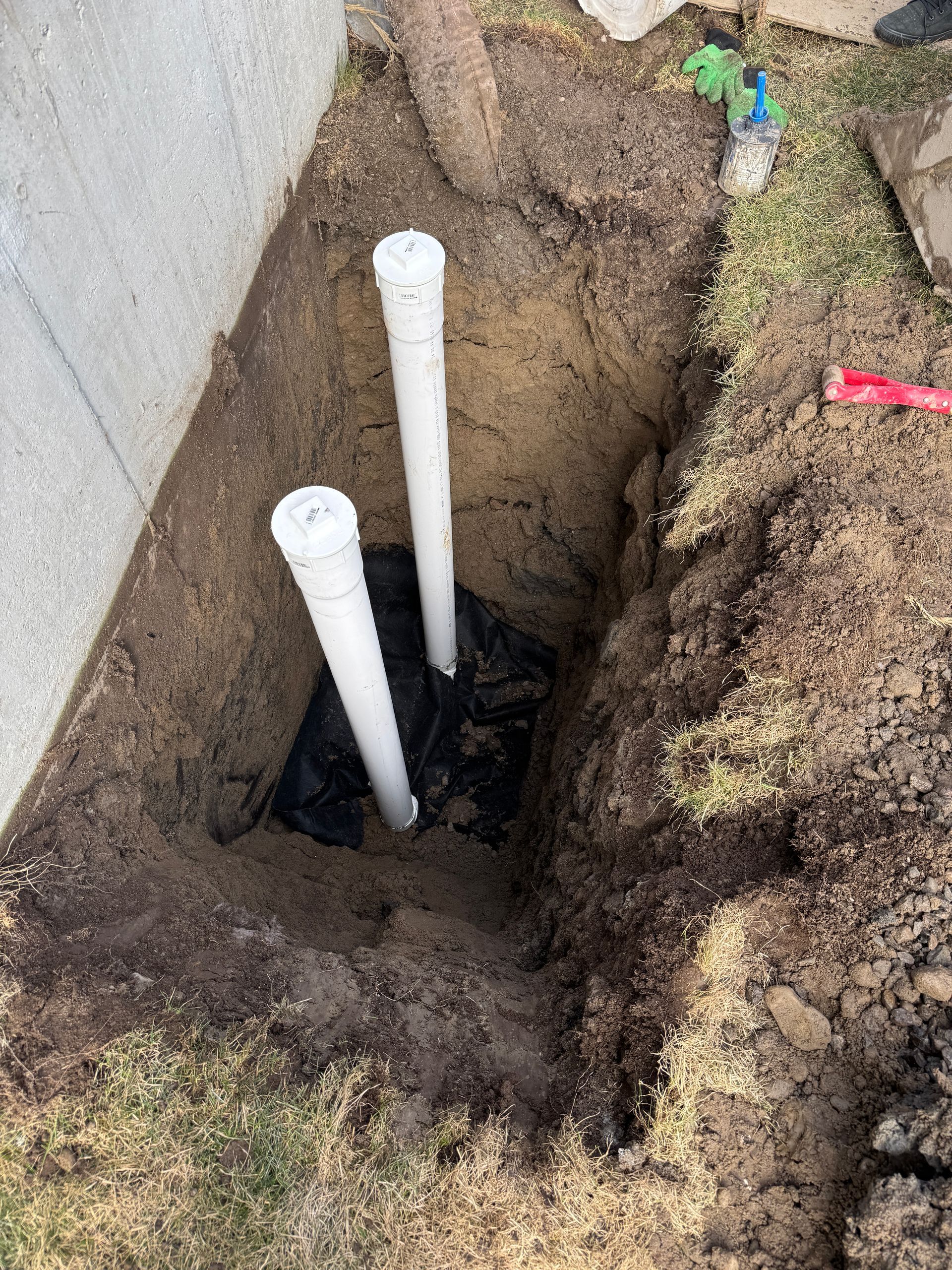 Deux tuyaux blancs sont posés dans un trou dans le sol.