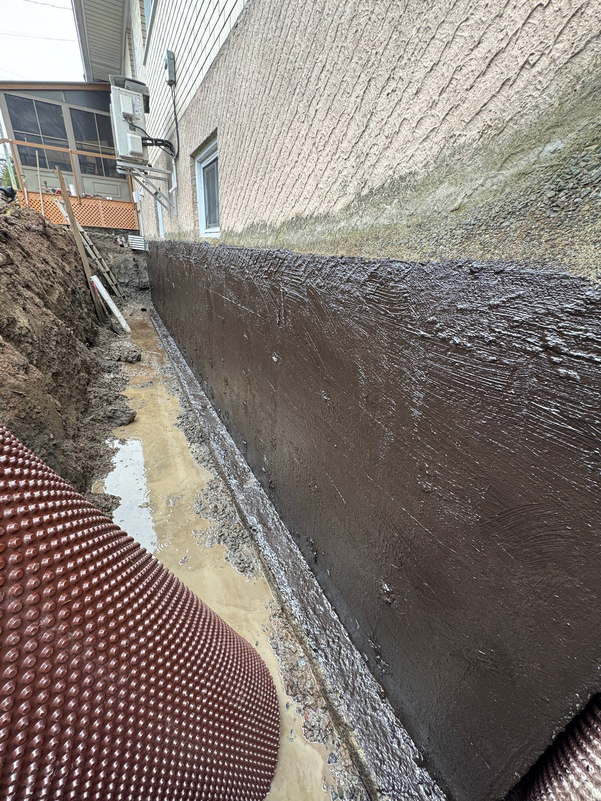 Un système de drainage est en cours d'installation sur le côté d'un bâtiment.