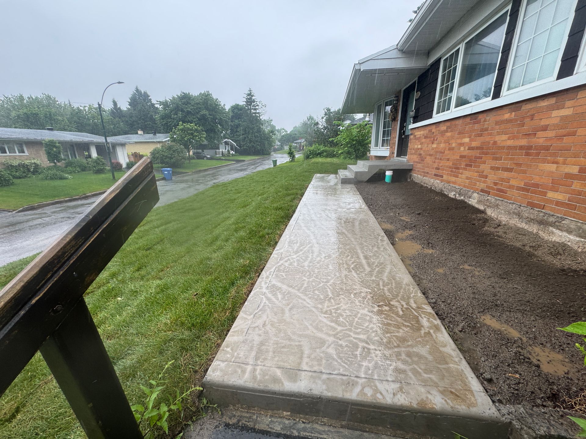 Une maison en briques avec une allée en béton devant elle.