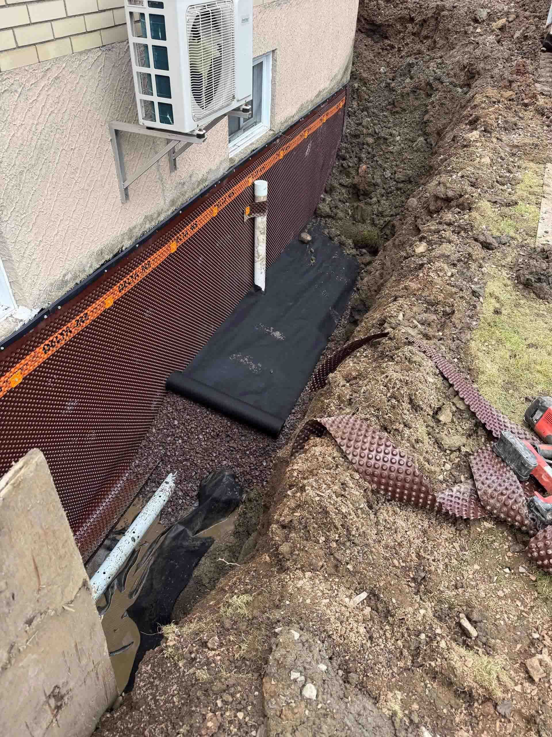 Une grande excavatrice orange est posée sur un champ de terre.
