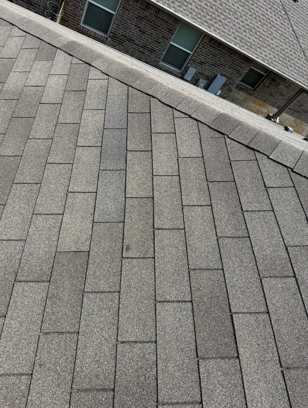 A close up of a roof with a brick building in the background.