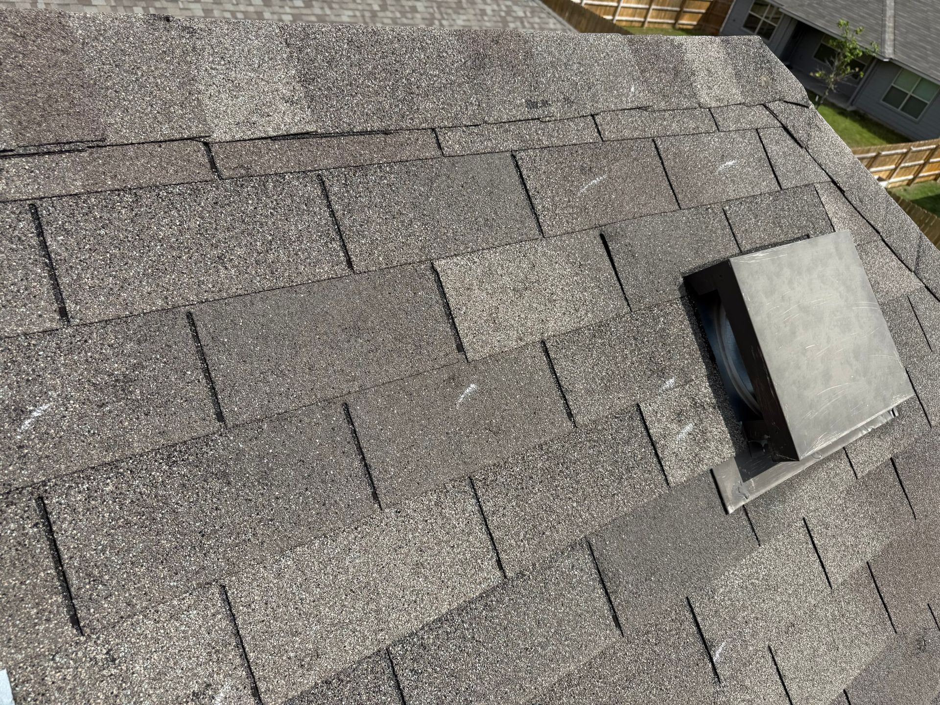 A close up of a roof with shingles and a vent on it.