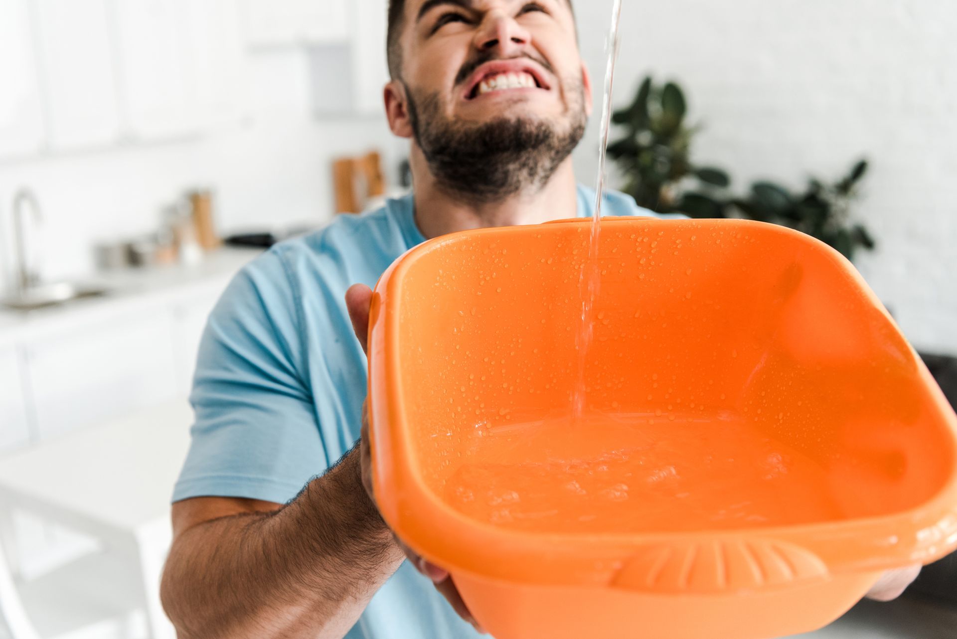 A man is holding a bowl of water with water coming out of it.