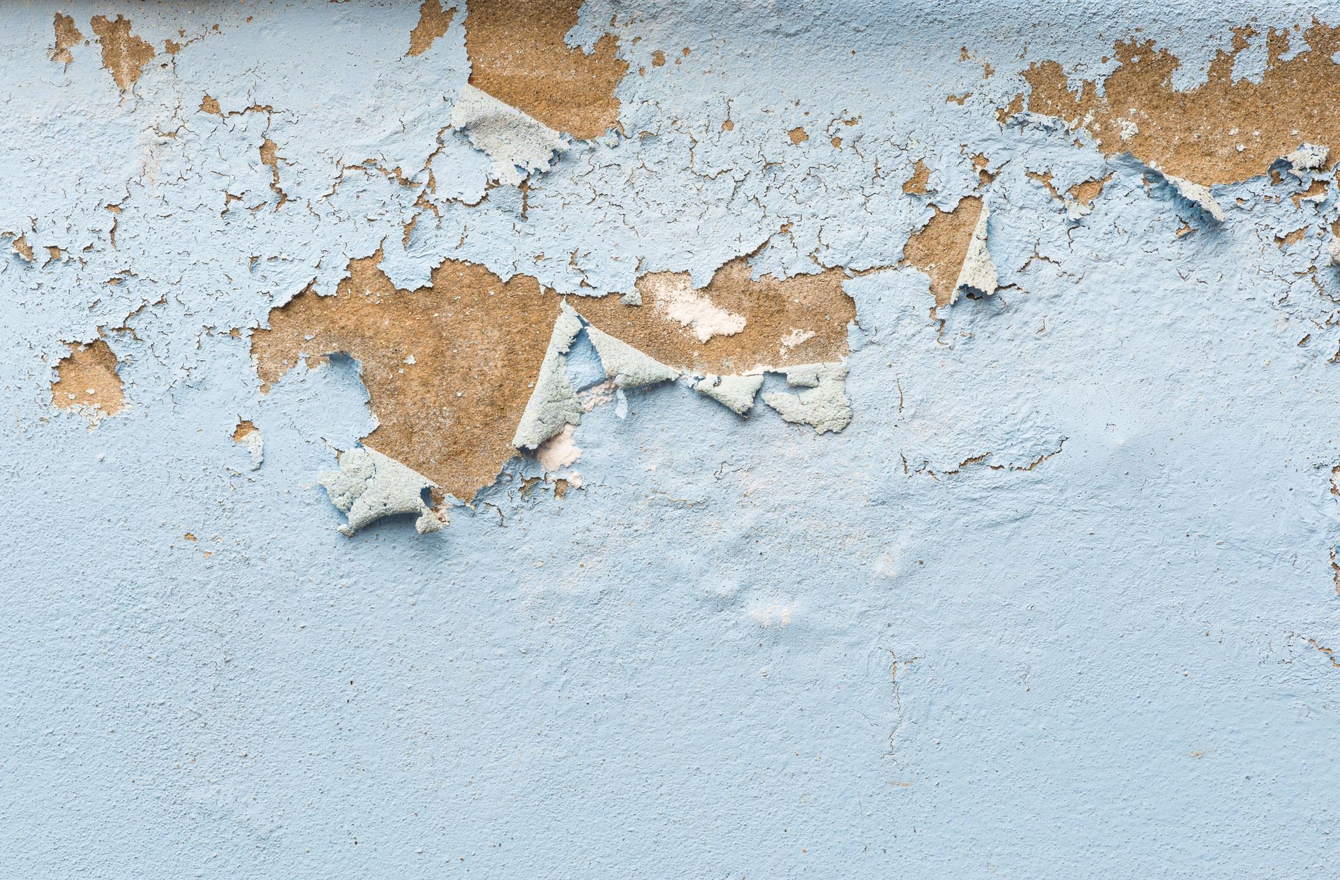 A close up of a blue wall with peeling paint