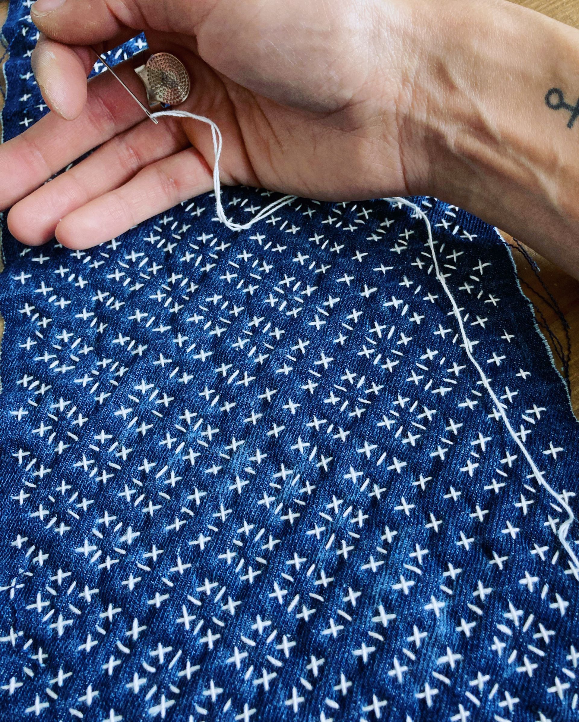 Sashiko stitching and blue Japanese textile with a white linen thread over blue patterned fabric by Silent Wave Studio