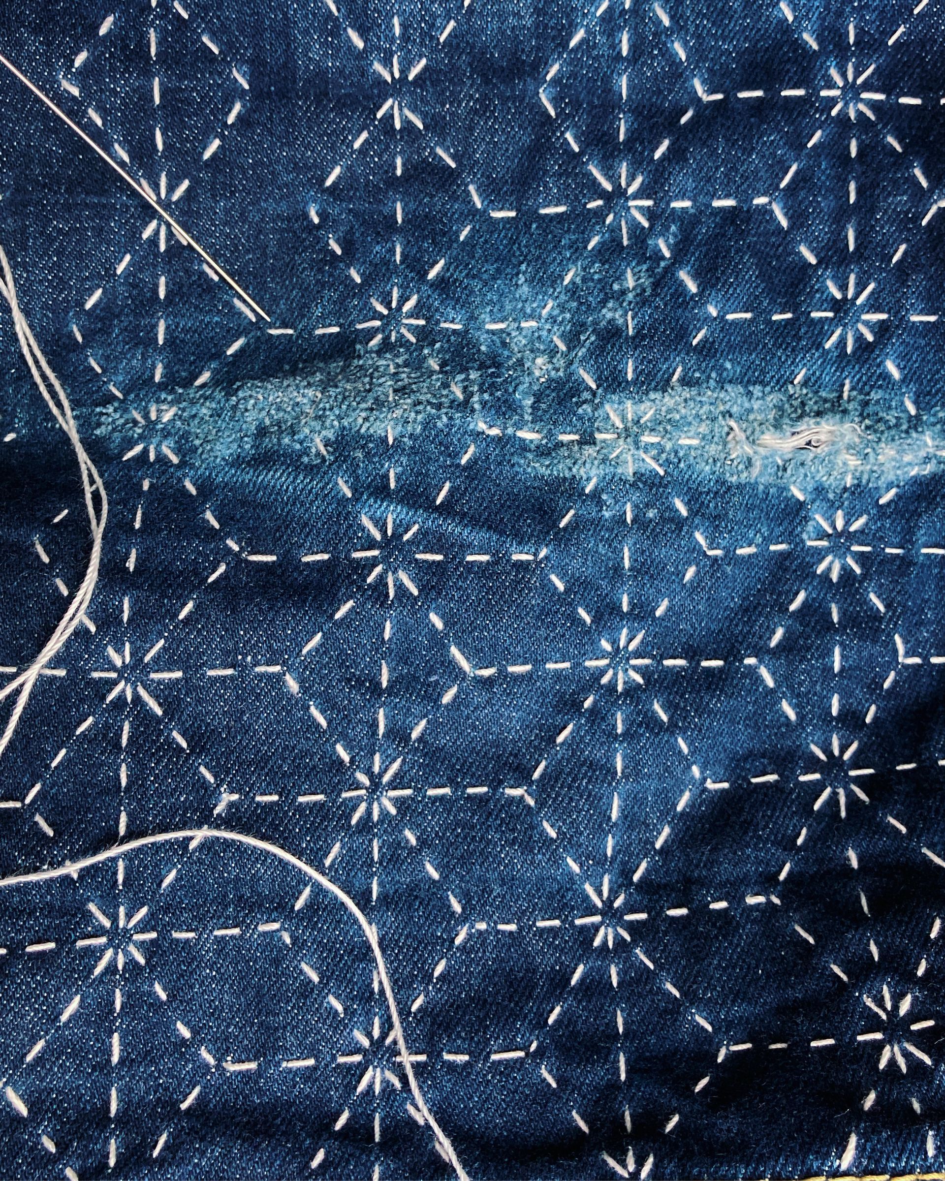 Close-up of dark blue sashiko patterned fabric with a light, worn horizontal streak across the center by Silent Wave Studio