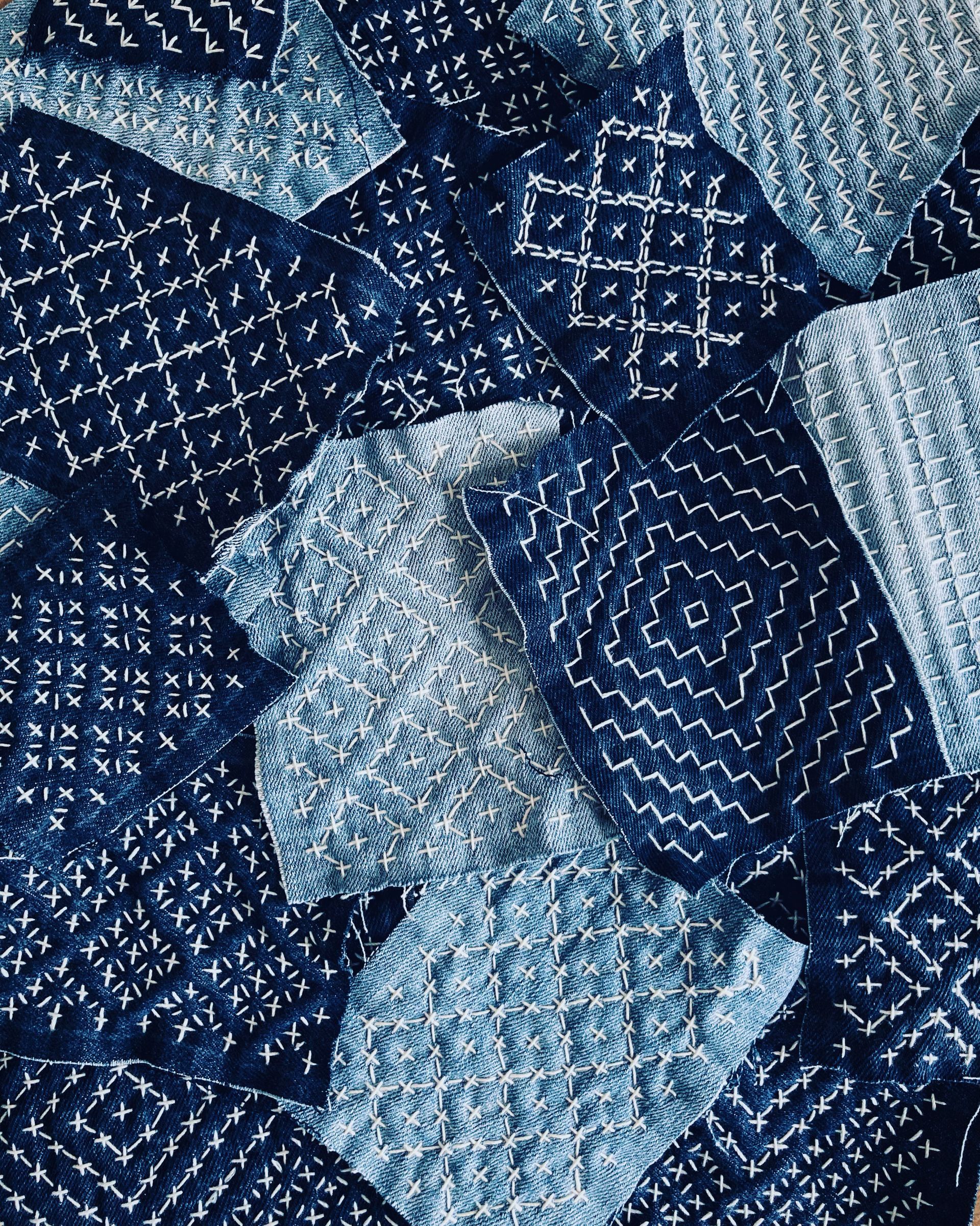 Close-up of blue patchwork denim fabric with stitched geometric patterns.