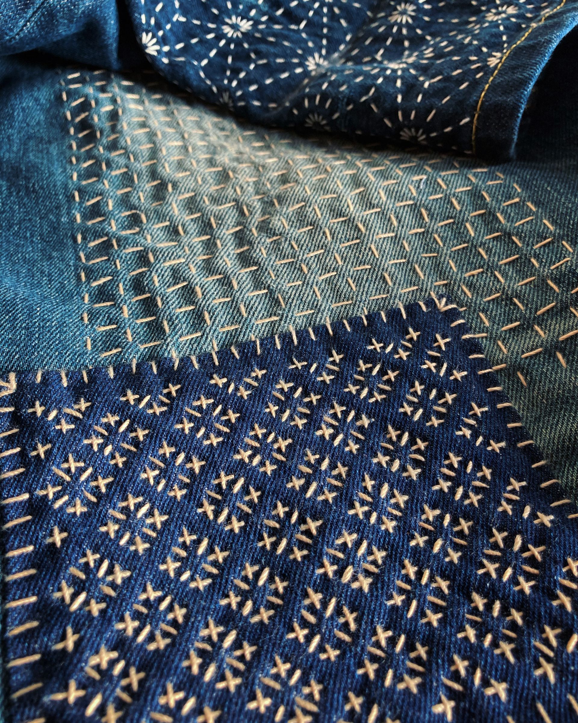 Close-up of folded blue patterned fabric with gold and cream geometric embroidery
