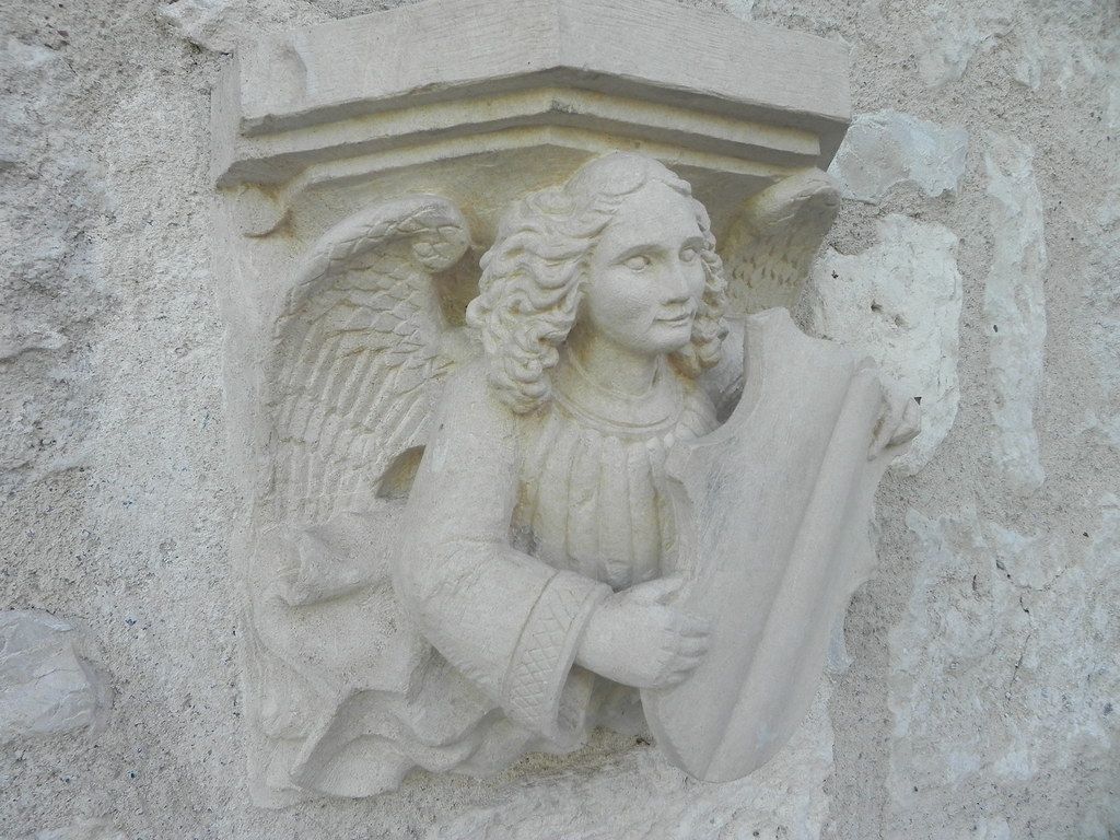 Stone relief of an angel playing a lute on a textured wall