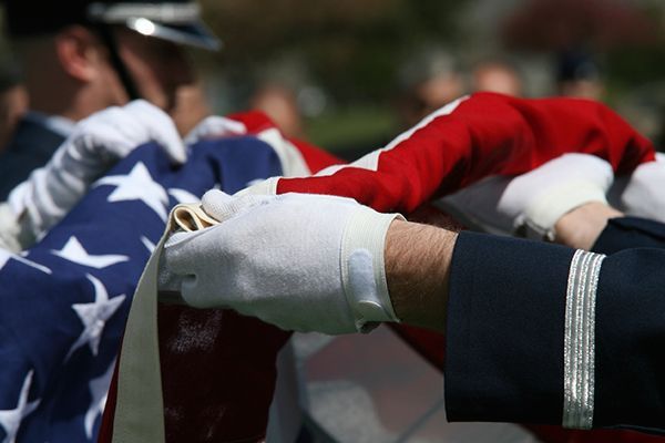 a man in a military uniform is holding an american flag