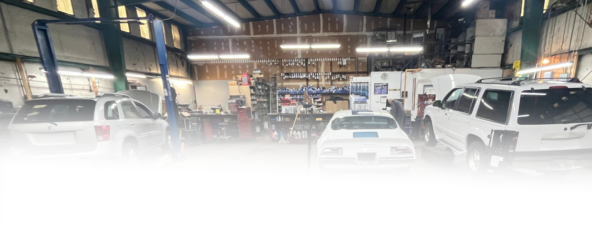 A workshop interior with three cars parked in bays under bright overhead lights. | Maynard's Auto Repair Service