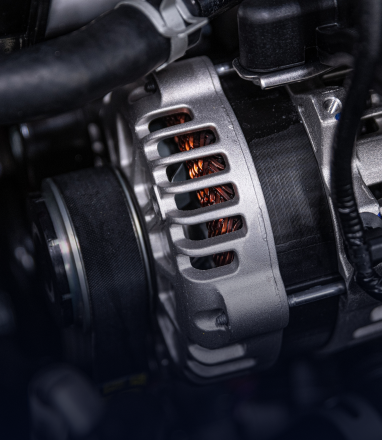 A close-up view of a car engine's metal alternator with visible copper wiring inside. | Maynard's Auto Repair Service