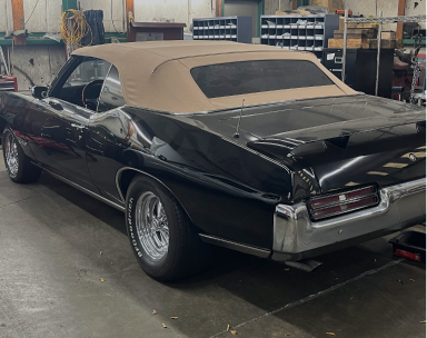A black vintage convertible with a tan soft top parked inside a garage. | Maynard's Auto Repair Service