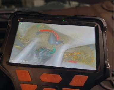 A handheld inspection camera screen shows a close-up view of debris. | Maynard's Auto Repair Service