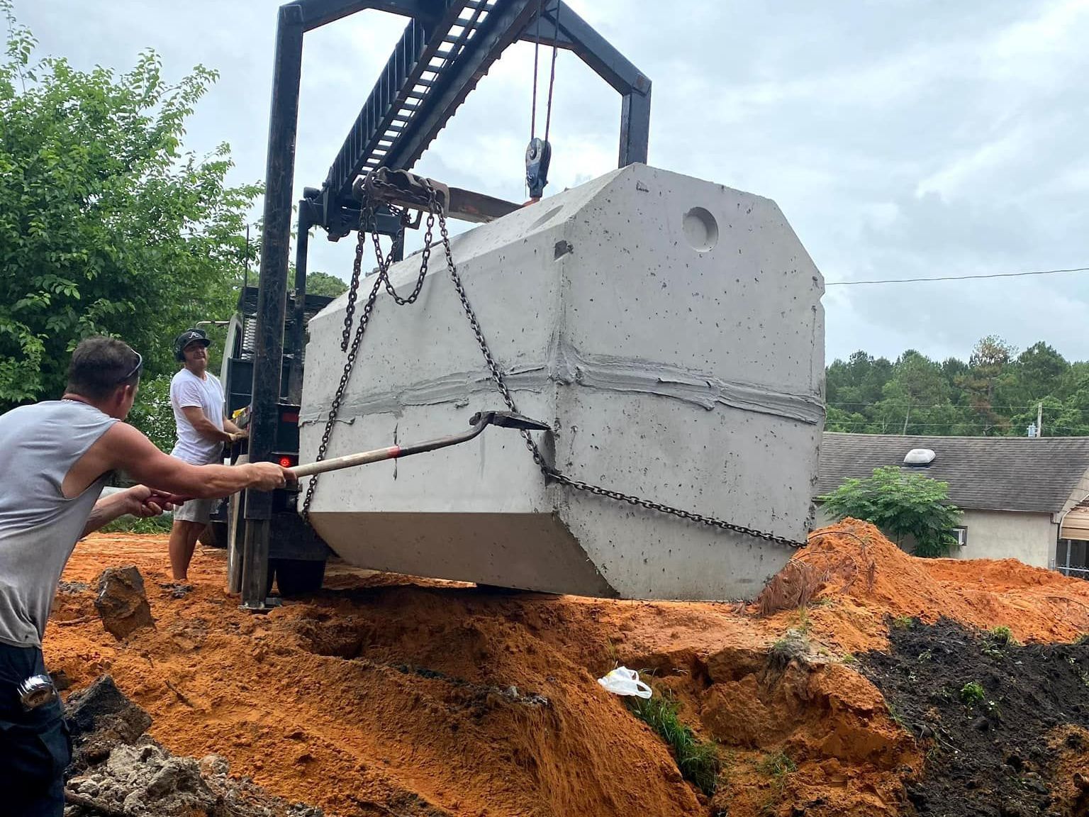 a large concrete septic tank is being lifted by a crane