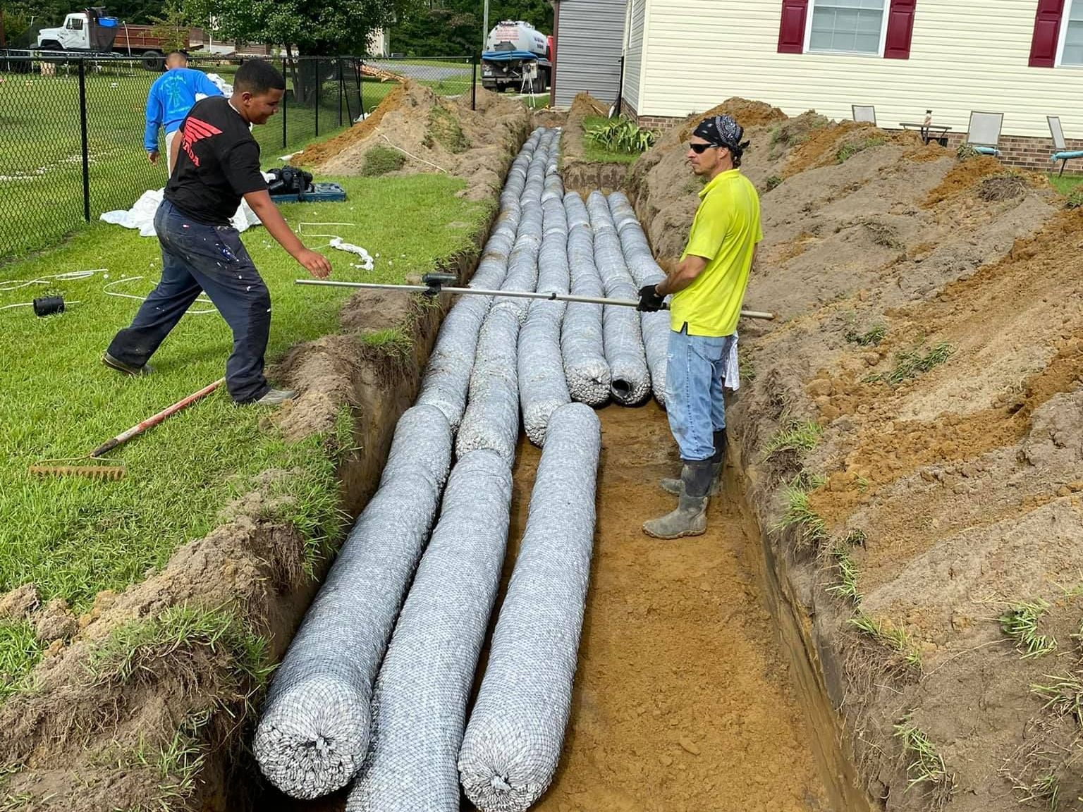 two men are working on a drainage system in the dirt