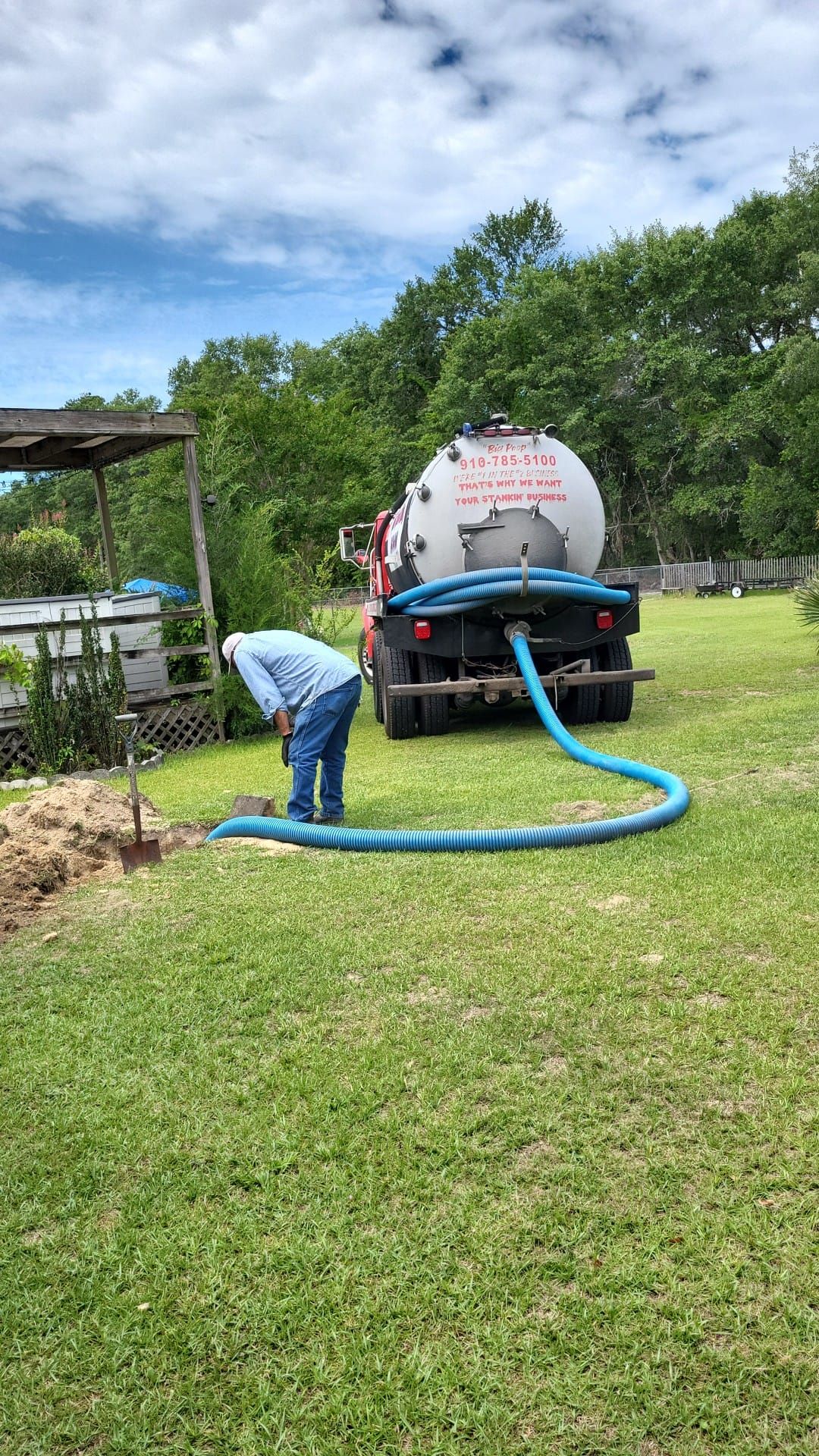 A man is digging a hole in the grass next to a septic tank.