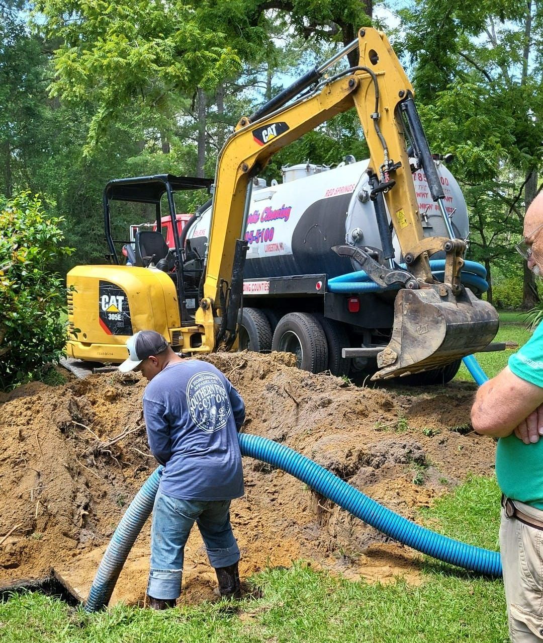 A man is pumping water into a hole next to a bulldozer.