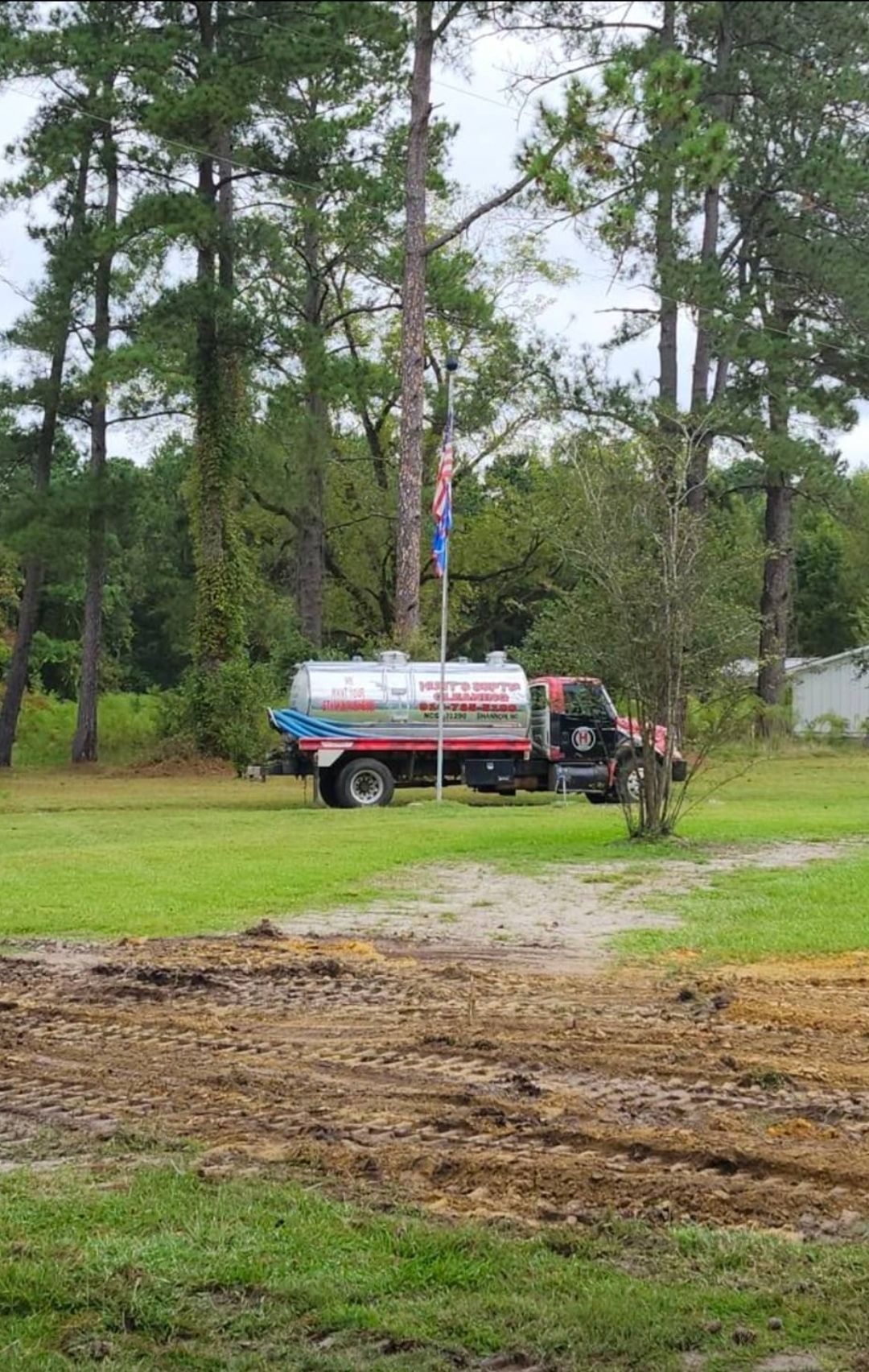 A tanker truck is parked in a grassy field.