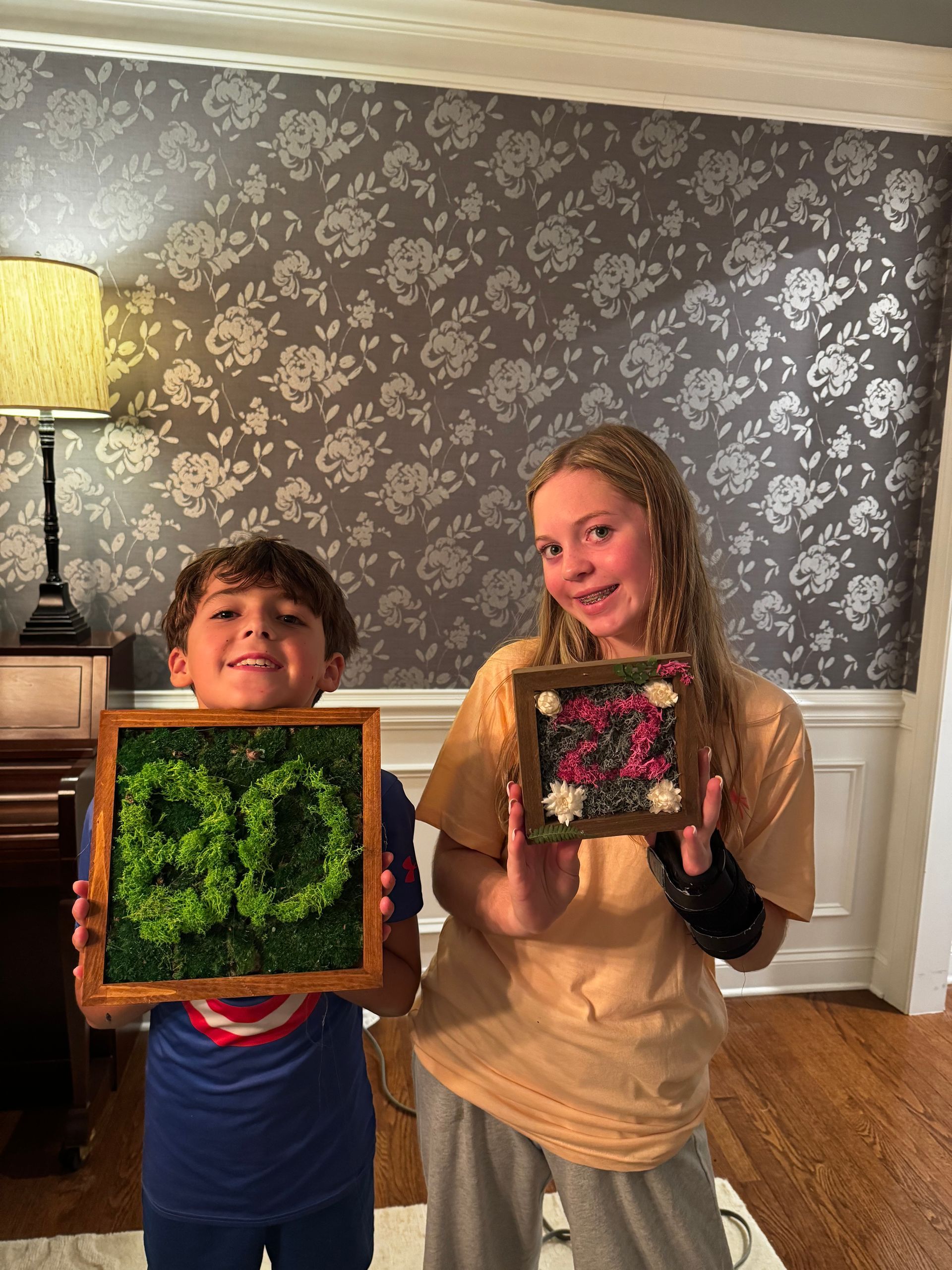 Two kids holding framed art. Boy has