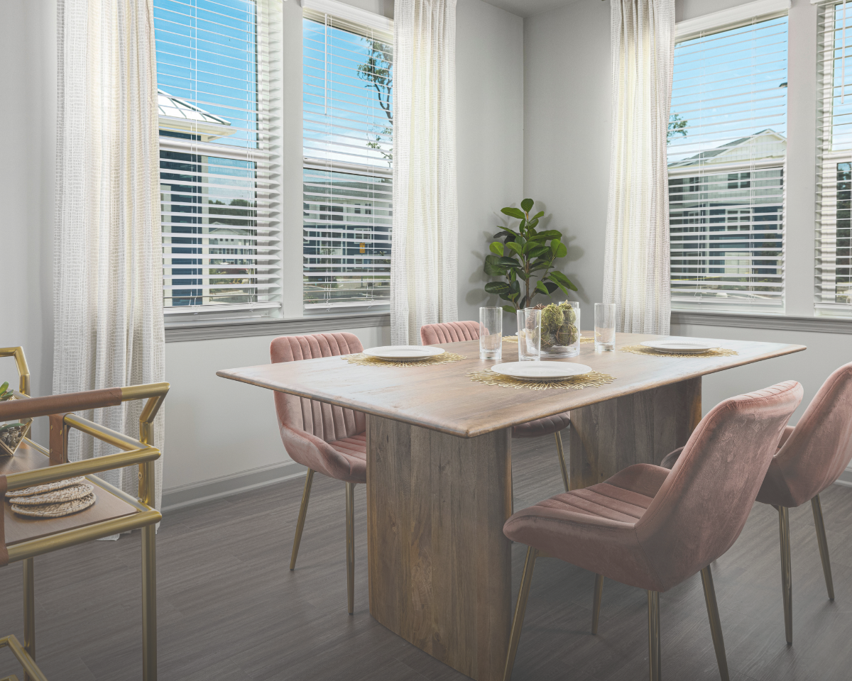 A dining room with a table and chairs and a bar cart.