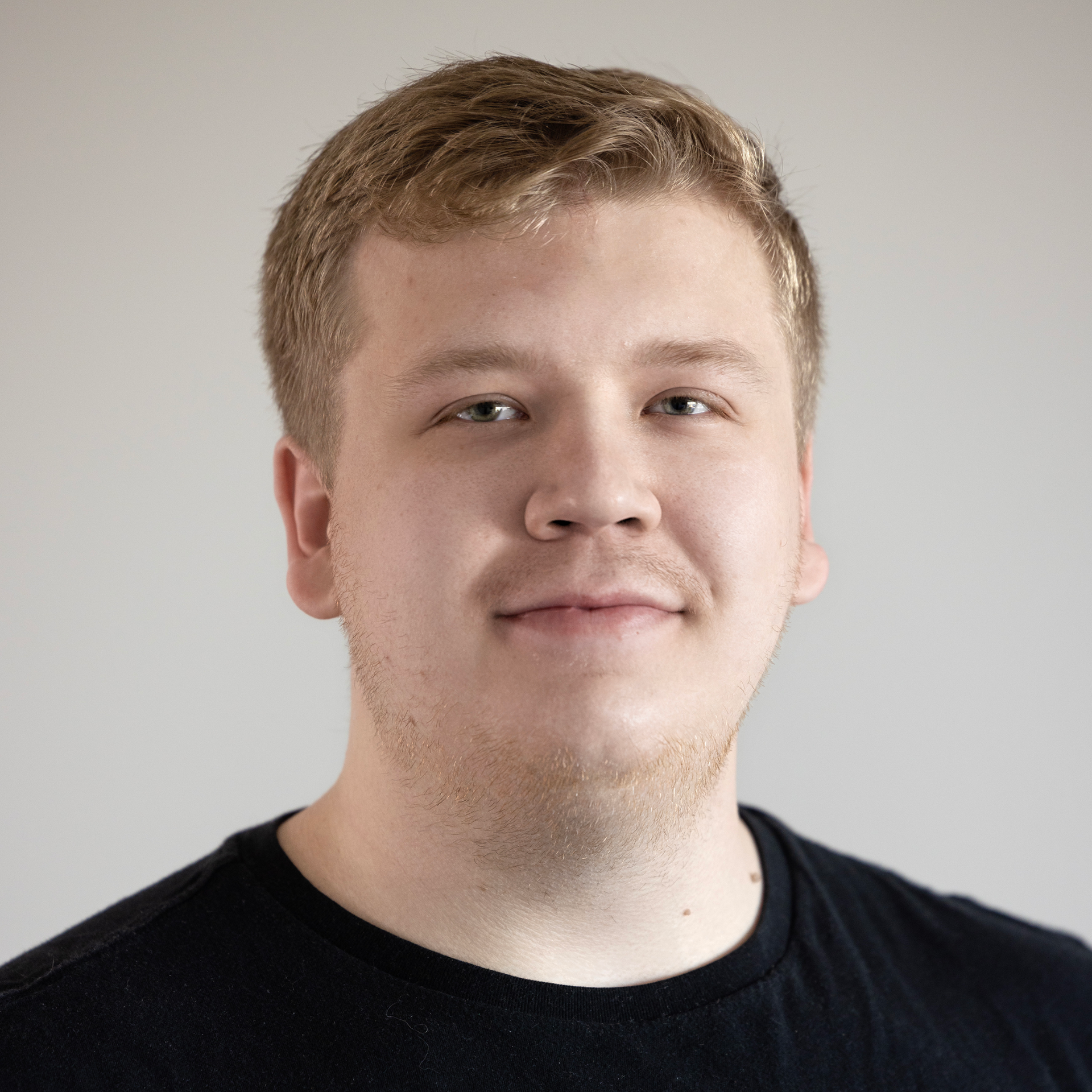 A young man wearing a black shirt is smiling for the camera.