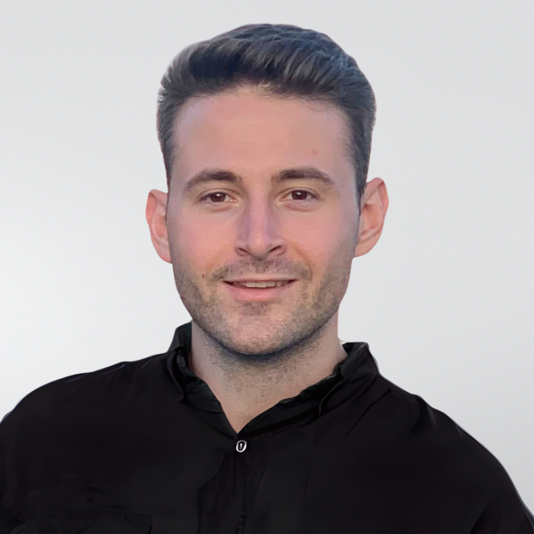 A young man in a black shirt is smiling in a black and white photo.