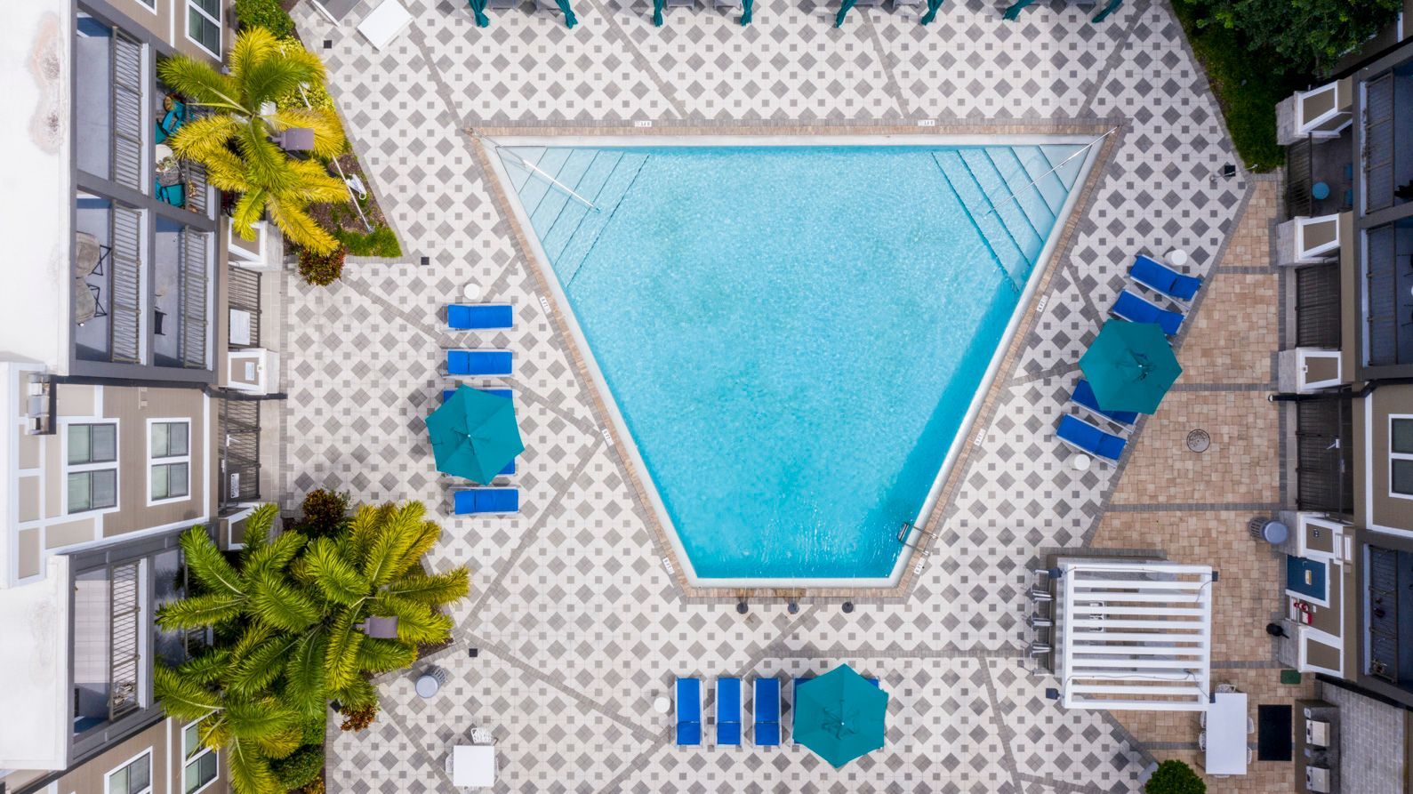 an aerial view of a large swimming pool surrounded by chairs and umbrellas