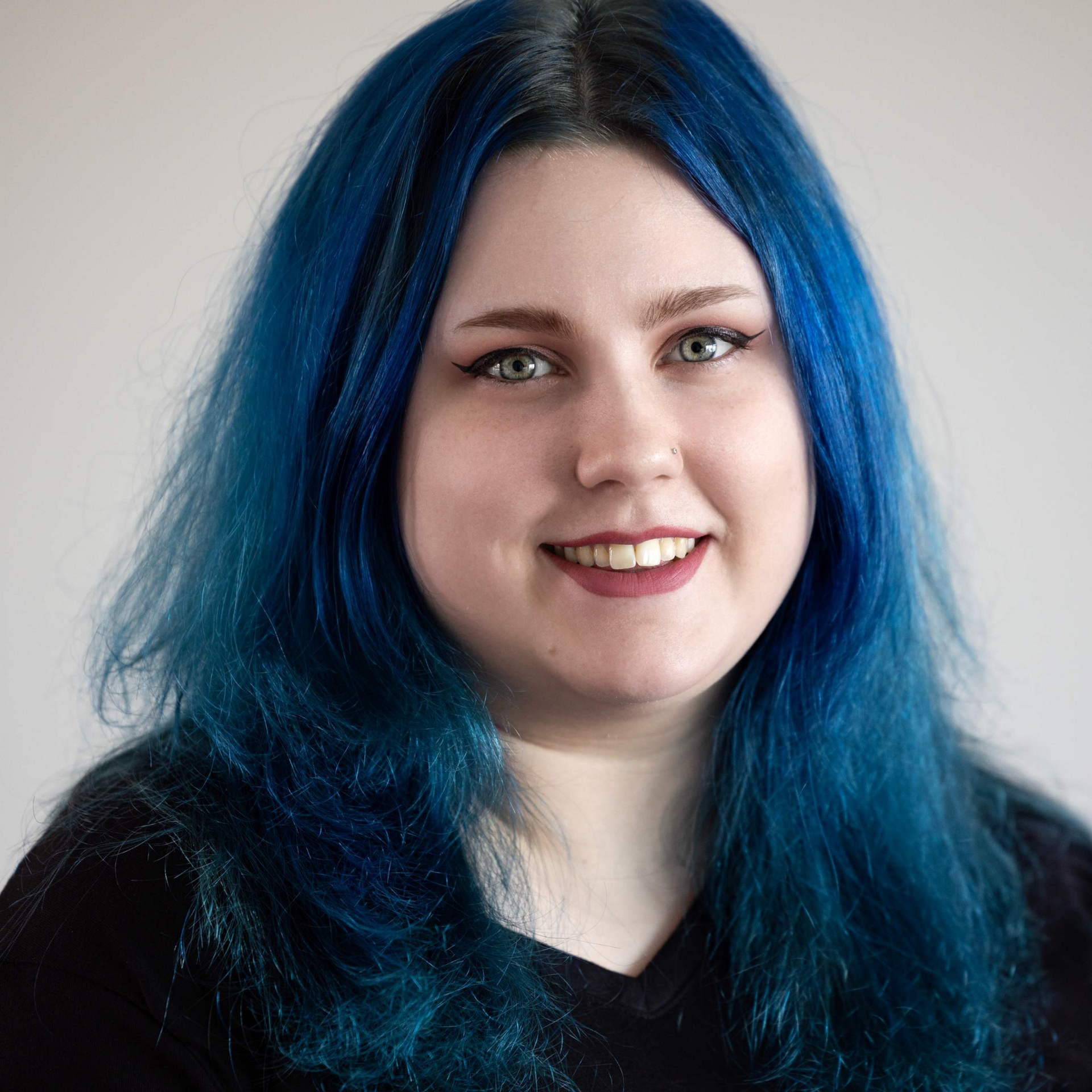 A woman with blue hair is smiling for the camera.