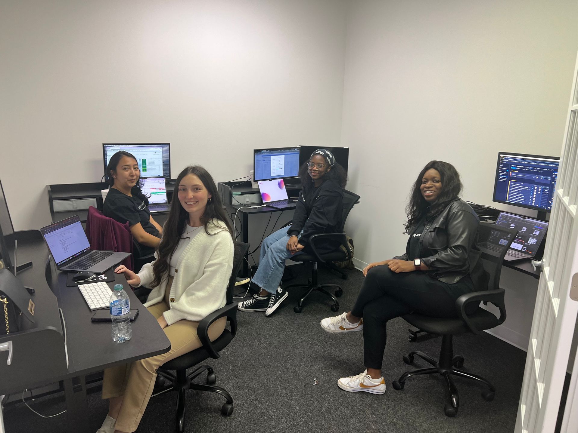 A group of women are sitting at desks in a room with computers.